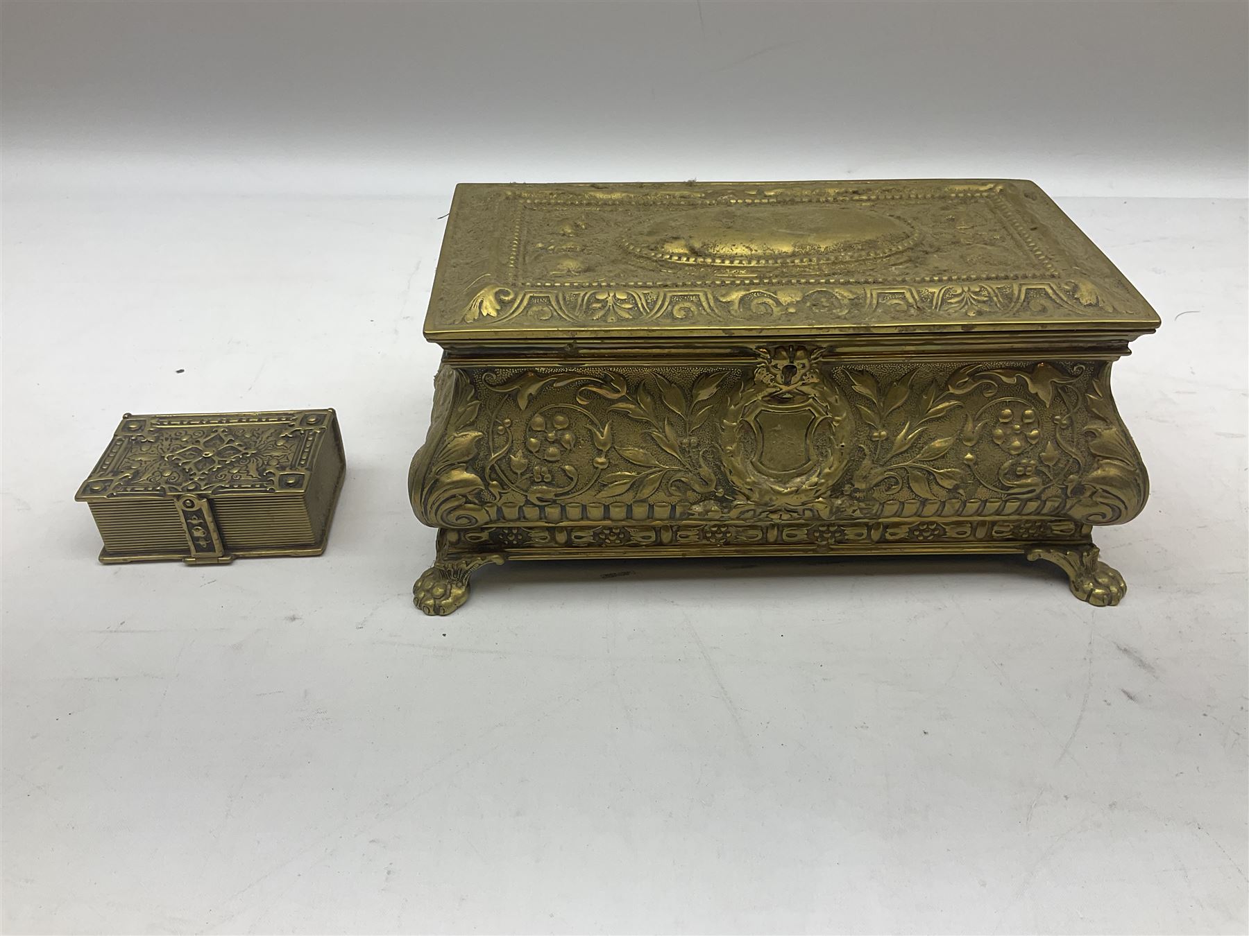 Collection of victorian and later brass desk accessories, to include a letter holder with cherub design, ink well of square form with hinged lid, brass table bell, brass casket with relief decoration, etc  