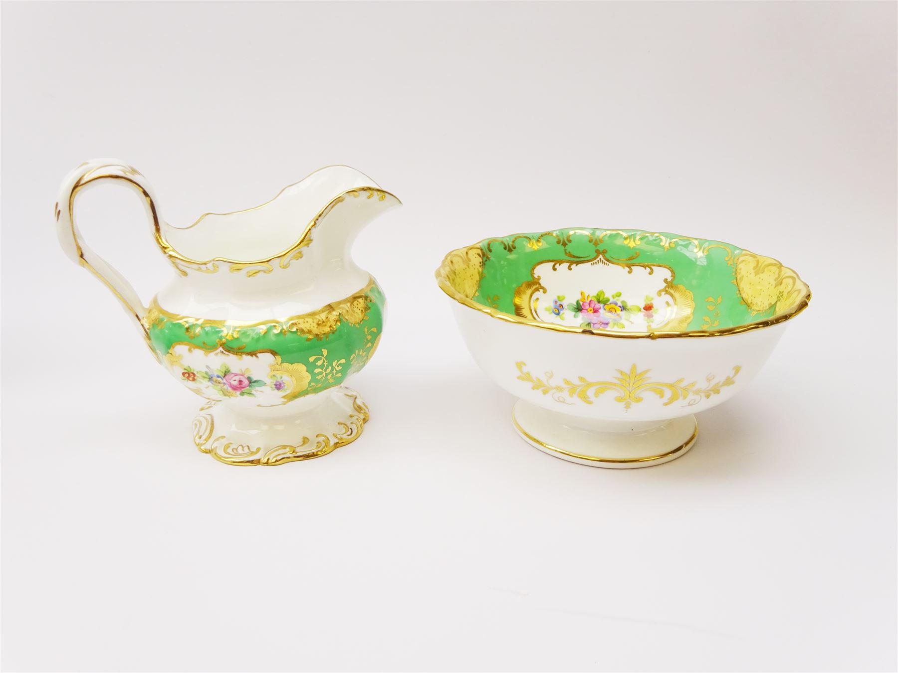 19th century Minton tea set, comprising twelve teacups, eleven saucers, fifteen side plates, cream jug, slop bowl, and two cake plates, decorated with panels of floral sprays, upon a green ground, heightened with gilt throughout, with printed puce mark beneath, and pattern number 5329
