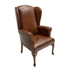 Beech framed wingback armchair, upholstered in brown fabric with stud work, on cabriole front supports