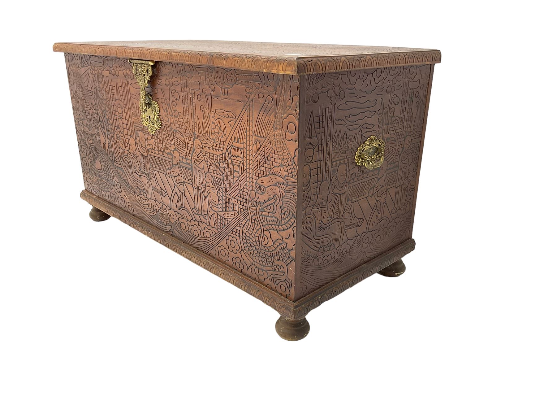 Hong Kong camphor wood chest, rectangular hinged top, carved all over with traditional scenes and dragon boats, on bun feet