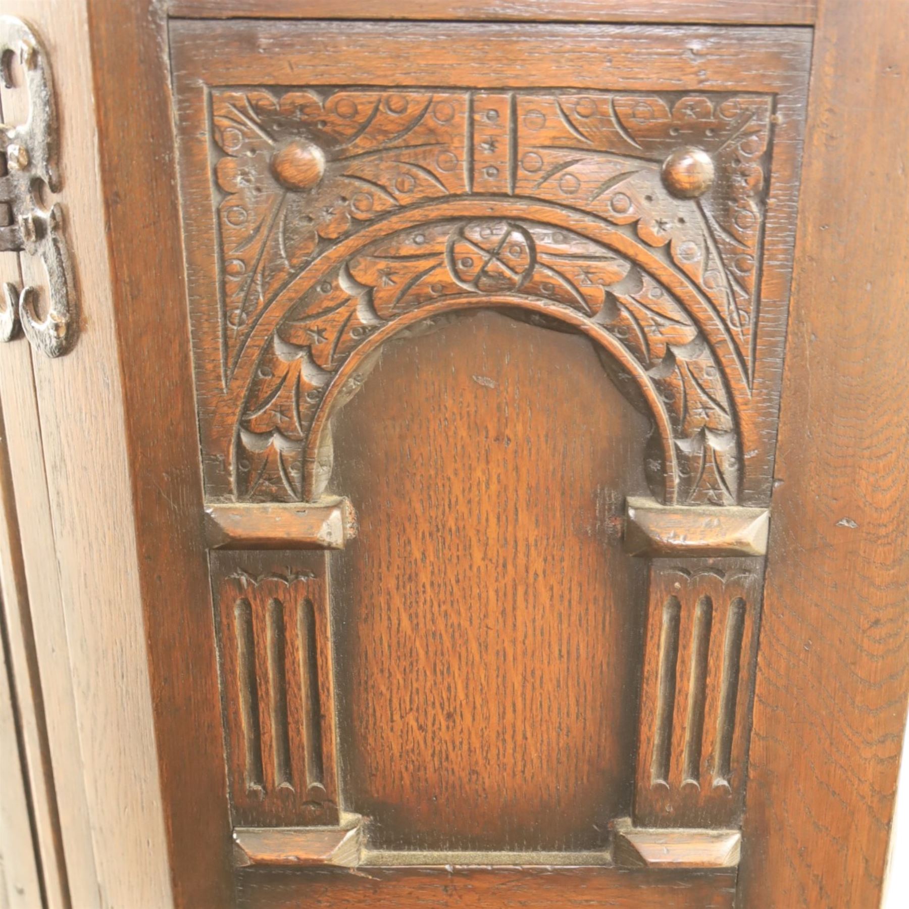 20th century dark stained oak hall robe, cantered sides enclosing a hooks and a shelf, panelled and carved sides, raised on stile supports