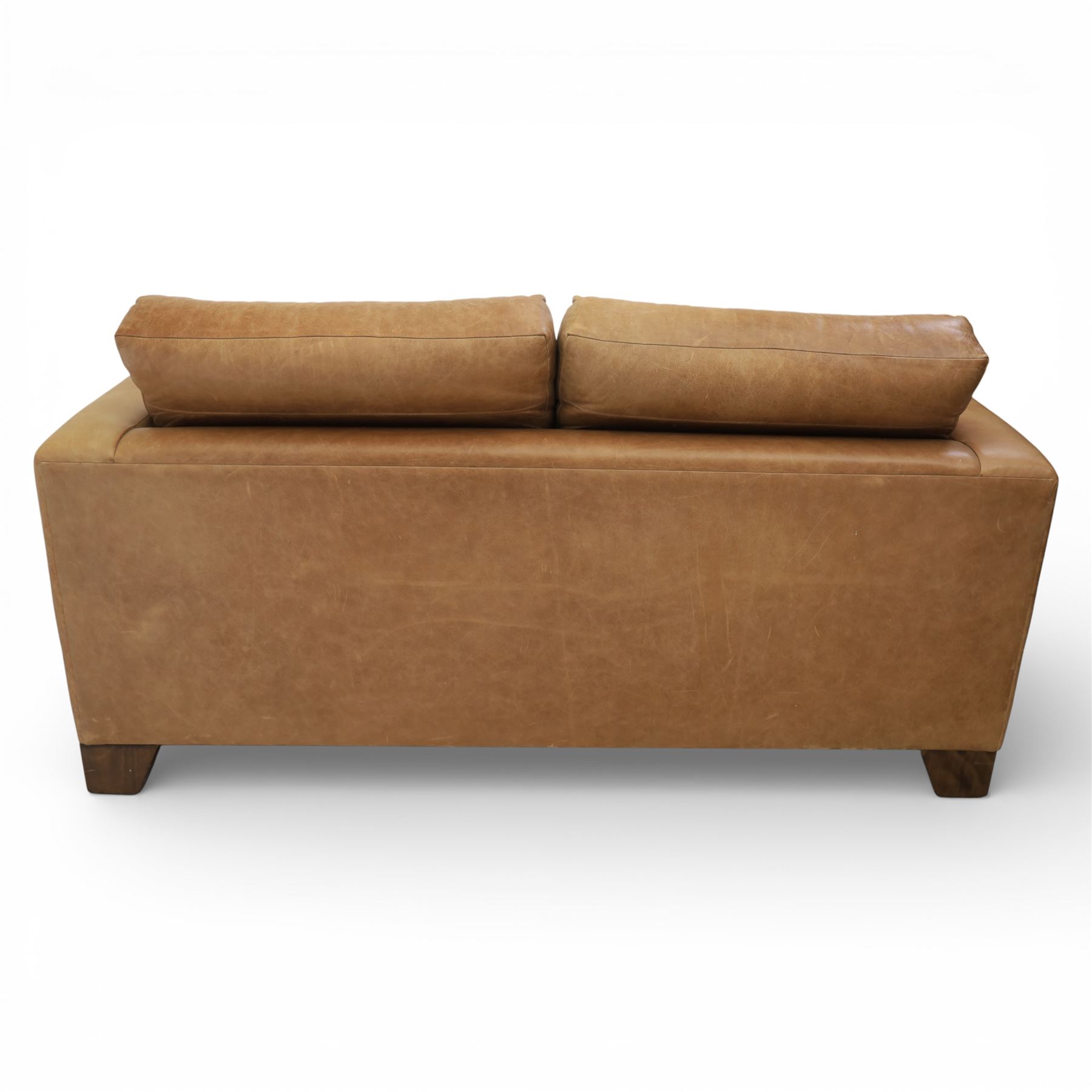 Modern two seat sofa in tanned leather, loose seat and base cushions, block arm rests above dark stained block supports 