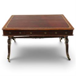 Regency inlaid mahogany and brass mounted library table, the rectangular top inset with gilt tooled burgundy leather writing surface, enclosed by  crossbanding and boxwood stringing with roundel corner motifs, above three cock-beaded frieze drawers to either side fitted with brass ring handles and brass escutcheons, the end friezes centred by applied brass foliate mounts, raised on twin reeded column supports over rectangular platform ends, united by a ring-turned stretcher, the reeded sabre legs terminating in brass caps and castors, one drawer bearing ivorine label 'Spillman & Co., St Martins Lane, London'