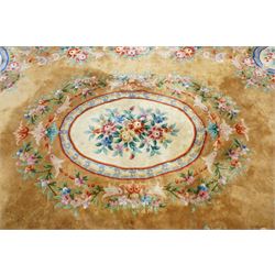 Chinese Aubusson/Savonnerie style hand-knotted carpet, ivory field with a central oval medallion issuing with stylized bouquets in shades of blush pink, pale blue, sage and green, enclosed by ribbon-tied floral garlands and conforming borders within narrow guard stripes, with cotton fringe ends 