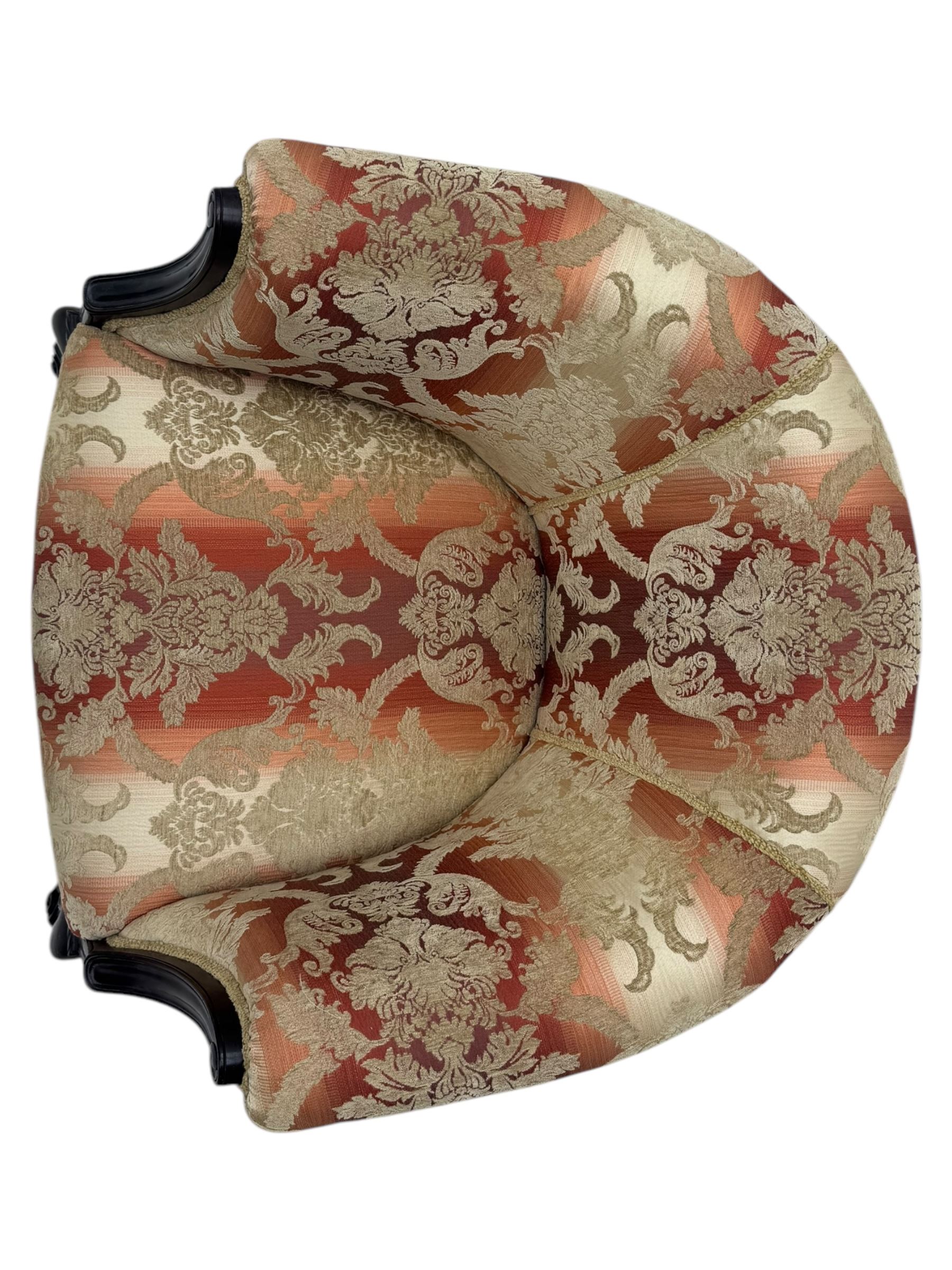 Early 20th century mahogany framed upholstered tub armchair, scrolled arms, upholstered in a damask-style fabric with foliate pattern, raised on cabriole front legs upon brass castors