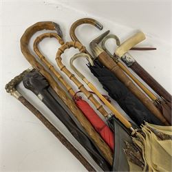 Four silver mounted walking canes, to include walking stick with horse's hoof silver terminal, silver collared stick with bone handle, umberella with silver terminal to handle etc, together with six further walking sticks and umberellas to include African ebonised walking stick with a carved top in the form of a man's head (10)