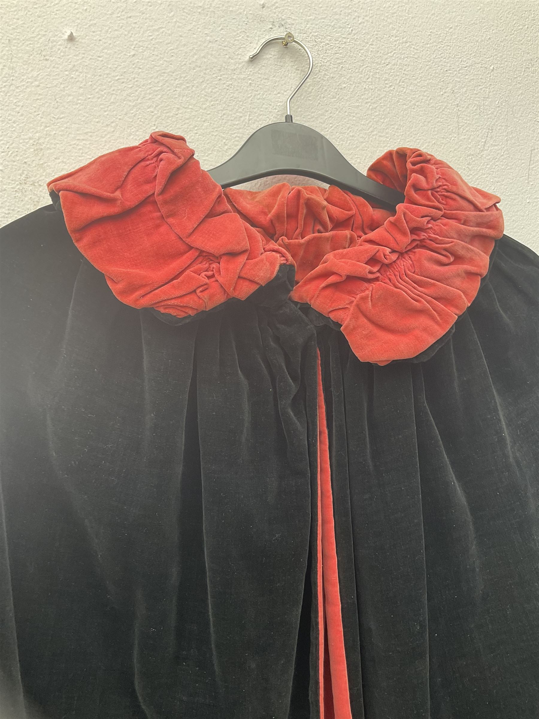 Full length 1930's childs black velvet cape, with ruched collar and red velvet lining, with a single button neck fastening 