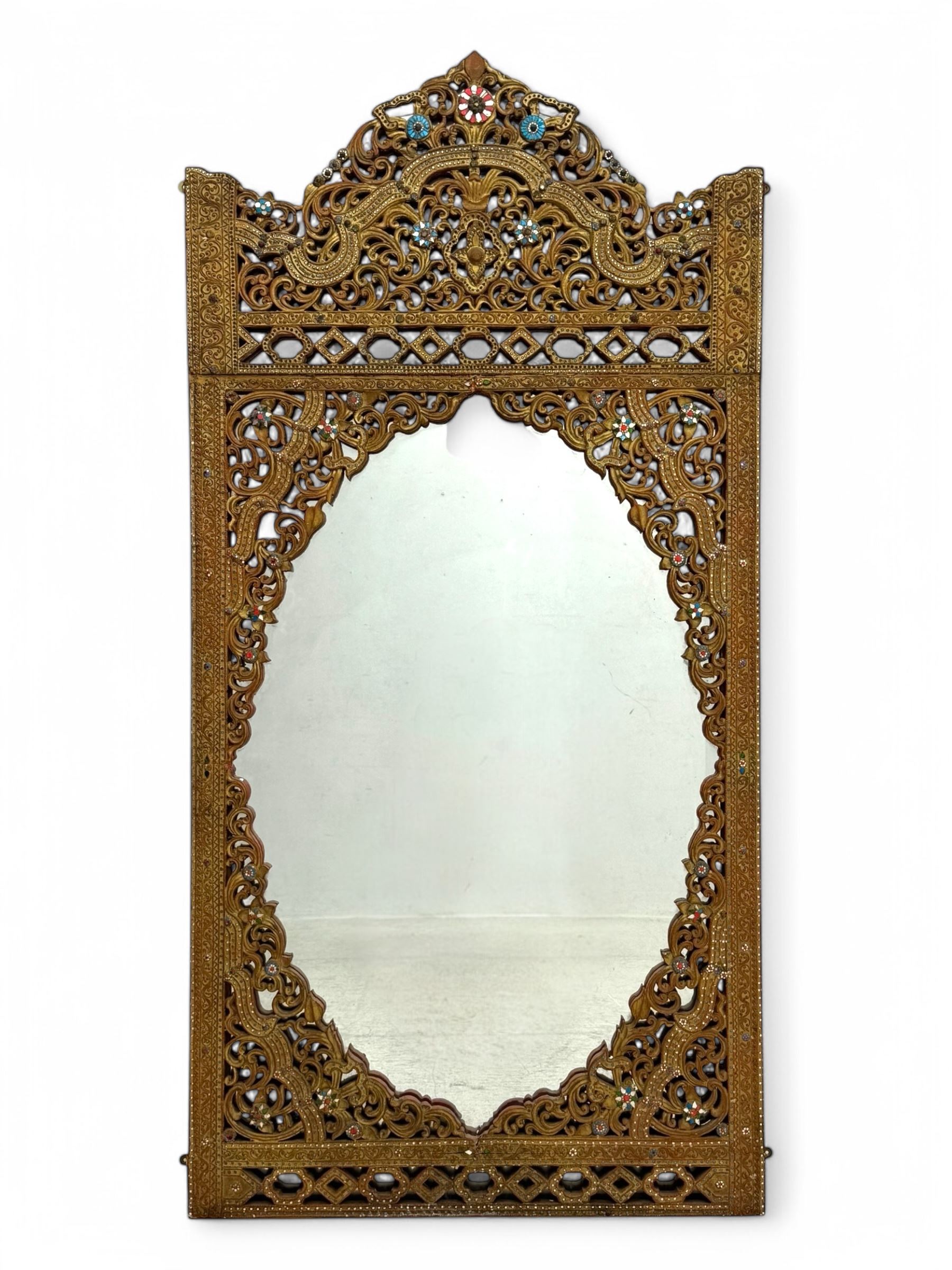 Large North African design carved and painted wall mirror, decorated with floral motifs, pierced foliate scrolls, inset mirrored panels, and colourful painted detailing, enclosing an oval bevelled mirror plate