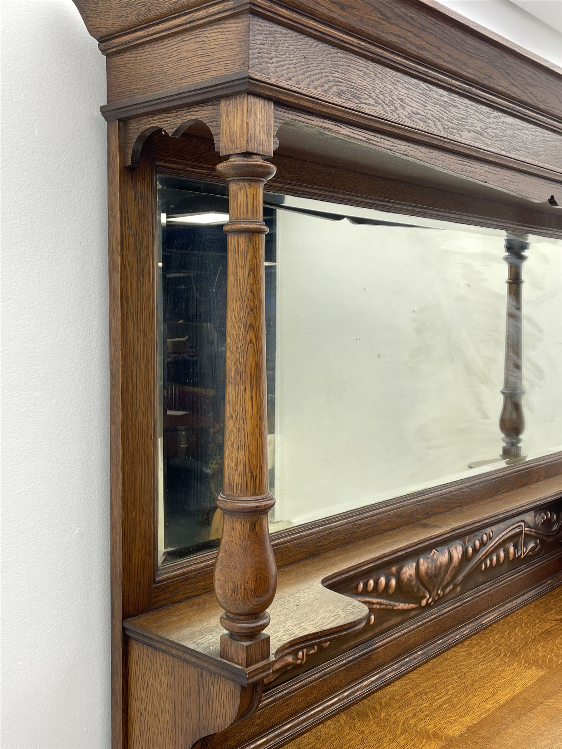 Arts and Crafts period oak mirror back dresser, projecting cornice above rectangular bevelled mirror and shelf, two turned supports, inset copper panel with embossed decoration, rectangular moulded top over two drawers and two panelled cupboard, moulded plinth base, brass and copper strappings and handles 
