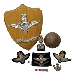 Parachute regiment - chrome crest on oak easel shield; three cloth badges; small silver plated figure; and pin badge; together with 10cm diameter cannon ball etc