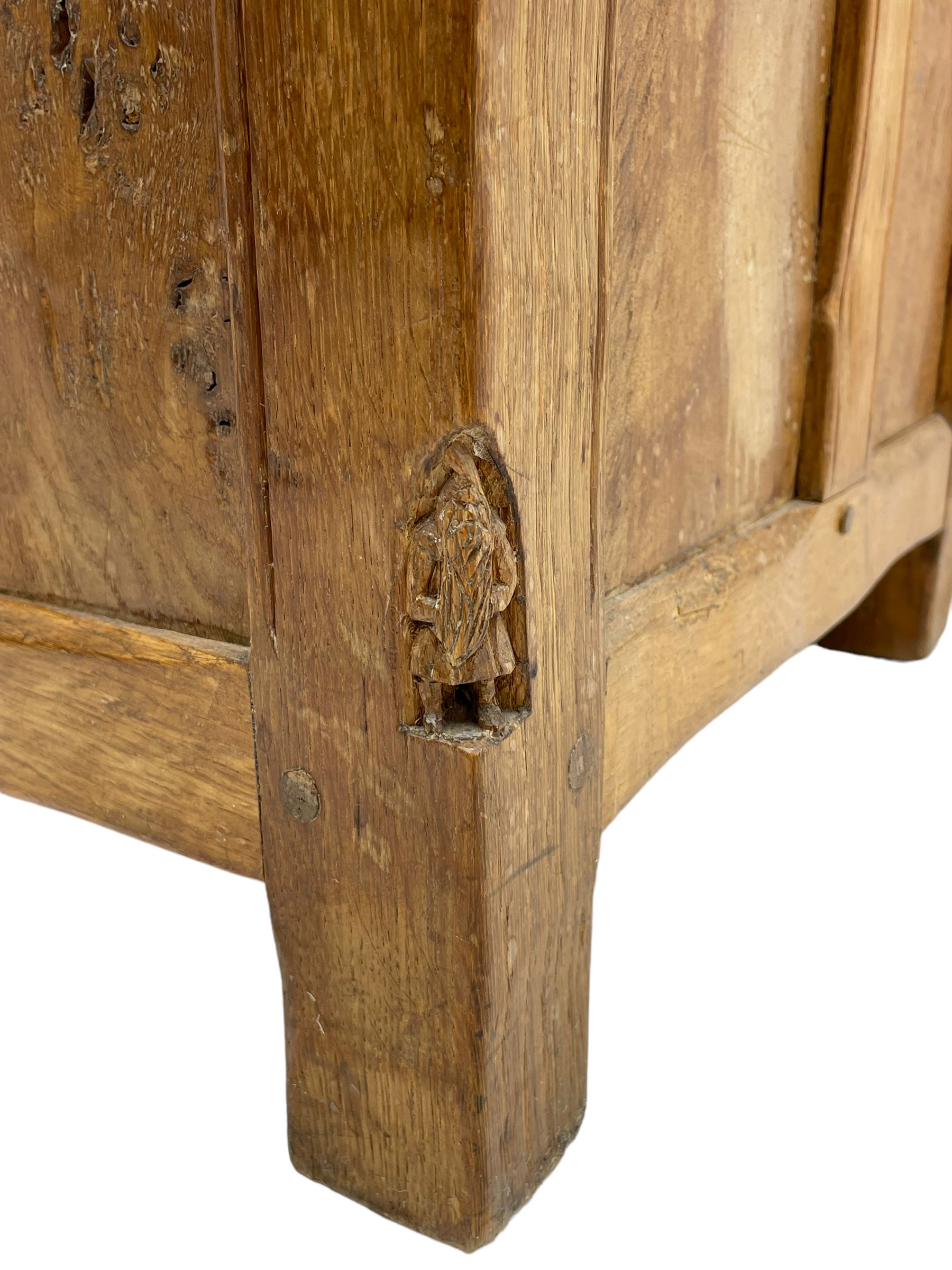Gnomeman - oak blanket box, all-over adzing, the hinged top over figured and burr panelled front, decorated with carved crenellations and arcade, carved with gnome signature, pierced handles to each end forming the central rail, wrought metal hinges, on stile supports, by Tom Whittaker, Littlebeck, Whitby