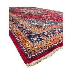 Persian Meshed red ground rug, central floral rosette medallion surrounded by trailing branch and stylised flower heads, repeating scrolling border