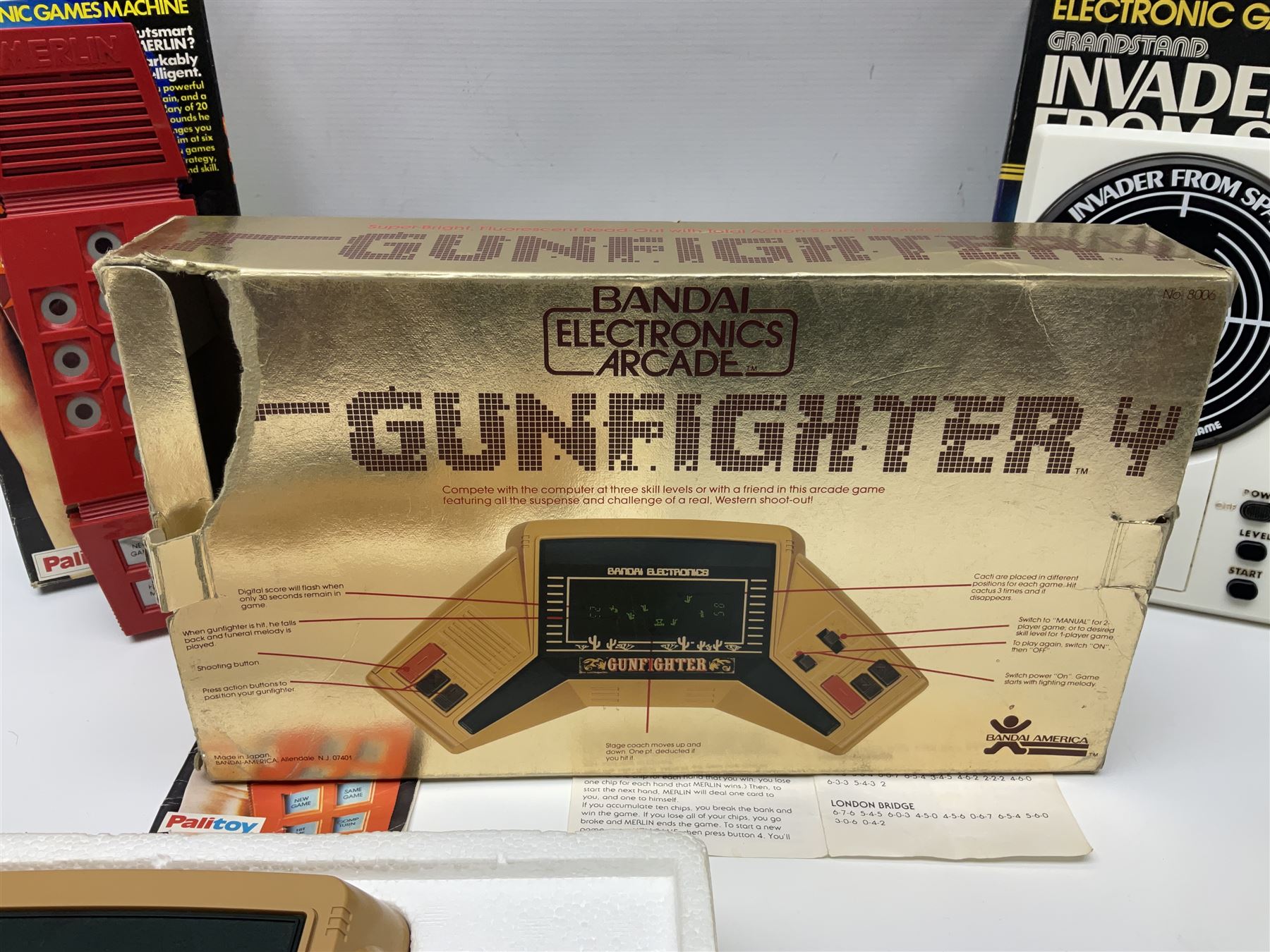 Three late 70s/early 80s handheld electronic games; Bandai Electronics Arcade ‘Gunfighter’ (1980), Grandstand ‘Invader From Space’ (1980), Palitoy ‘Merlin The Electronic Game Machine’ (1979) with game sheet and instruction booklet, all with original boxes (3) 