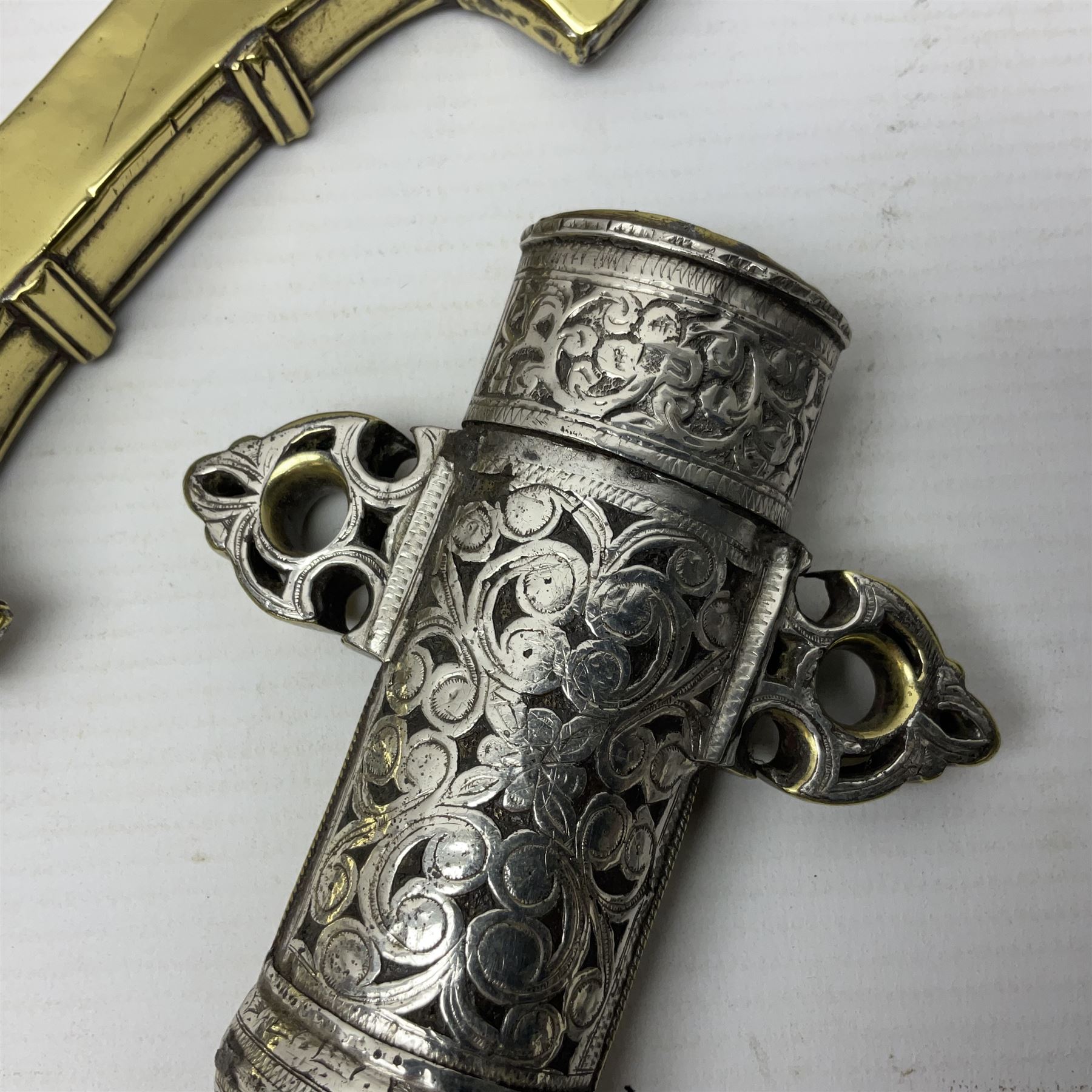 Moroccan jambiya dagger with 24.5cm plain curved blade stamped LONDON to the ricasso area, the hilt and scabbard overlaid with plain sheet brass to the back and ornate silver coloured metal to the front; waisted grip and arched pommel; two pyramid mounts to the scabbard L41cm overall; large billhook with curving blade and stacked leather washer grip; and a reproduction halberd blade (3)