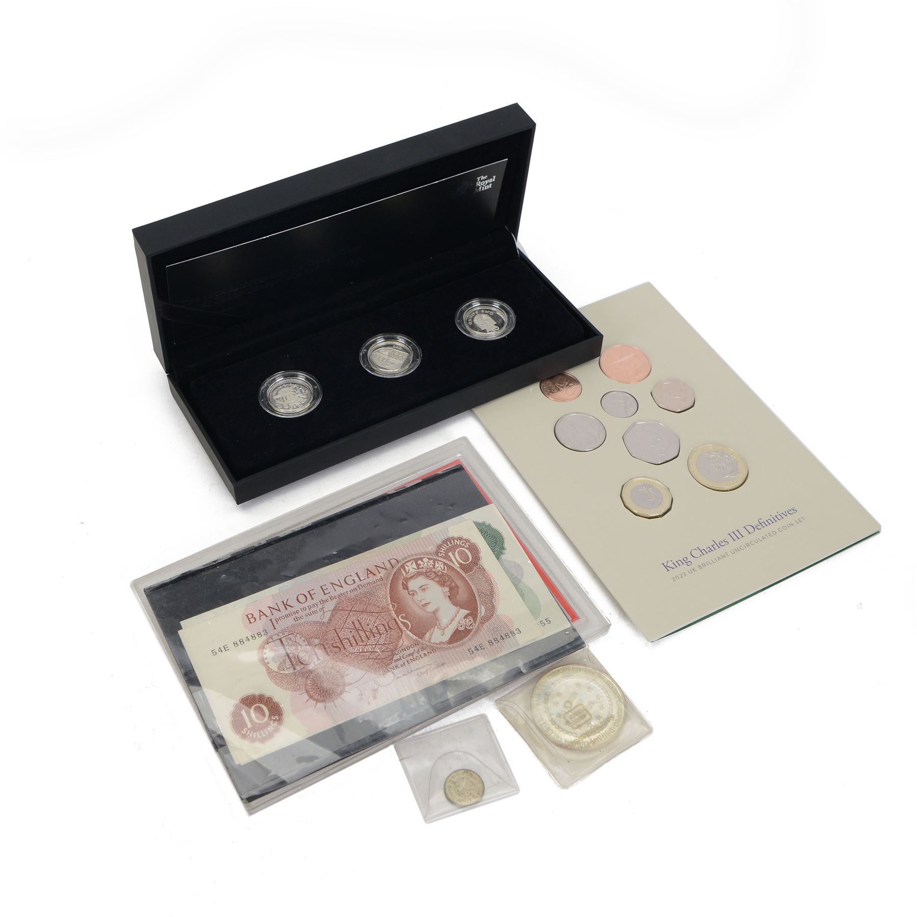 The Royal Mint United Kingdom 2013 'The 30th Anniversary Of The £1 Coin' silver proof three-coin set, 2023 brilliant uncirculated coin set, European Union silver thaler coin, King George VI 1941 silver threepence, 'Farewell to £.s.d. Coinage' set, and four Bank of England banknotes