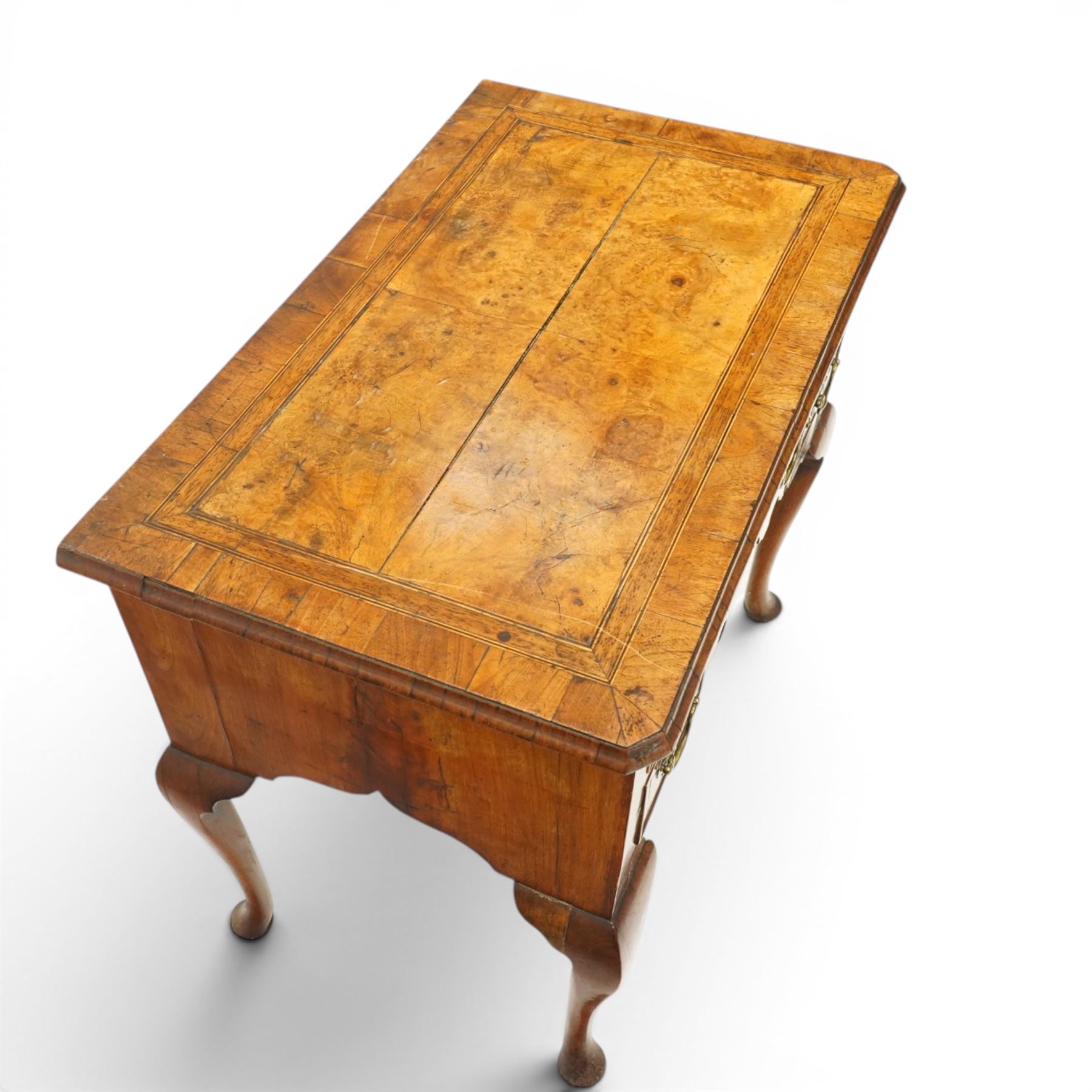 18th century figured and burr walnut lowboy, the rectangular canted top with book-matched veneer and crossbanding with moulded edge, fitted with an assortment of five cock-beaded drawers with original pierced brass handle plates, over a shaped apron, raised on cabriole supports with pad feet