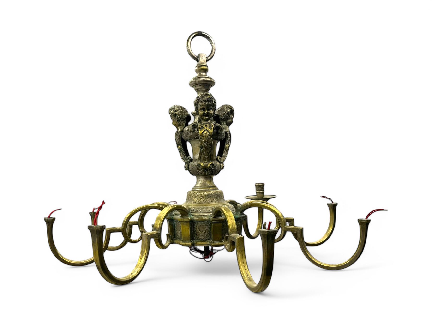 Early 20th century cast brass chandelier, the main baluster-form body surmounted by a lobed finial, with three cherubic heads and foliate scrollwork around the upper section, eight sweeping branches for lights