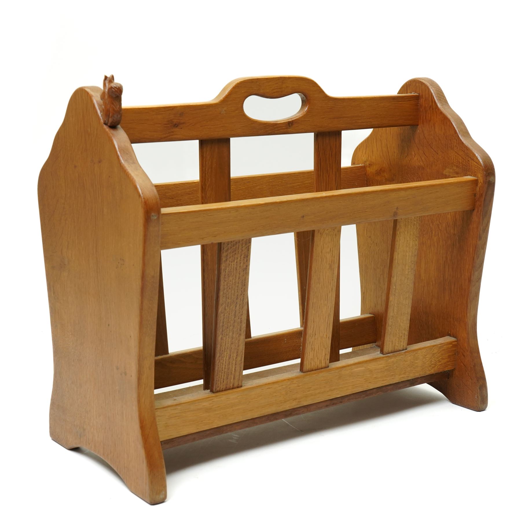 Squirrelman - oak magazine rack, the shaped ends enclosing a central slatted support with carrying aperture, enclosed by slatted sides and base, with carved squirrel signature, by Wilfrid Hutchinson of Husthwaite