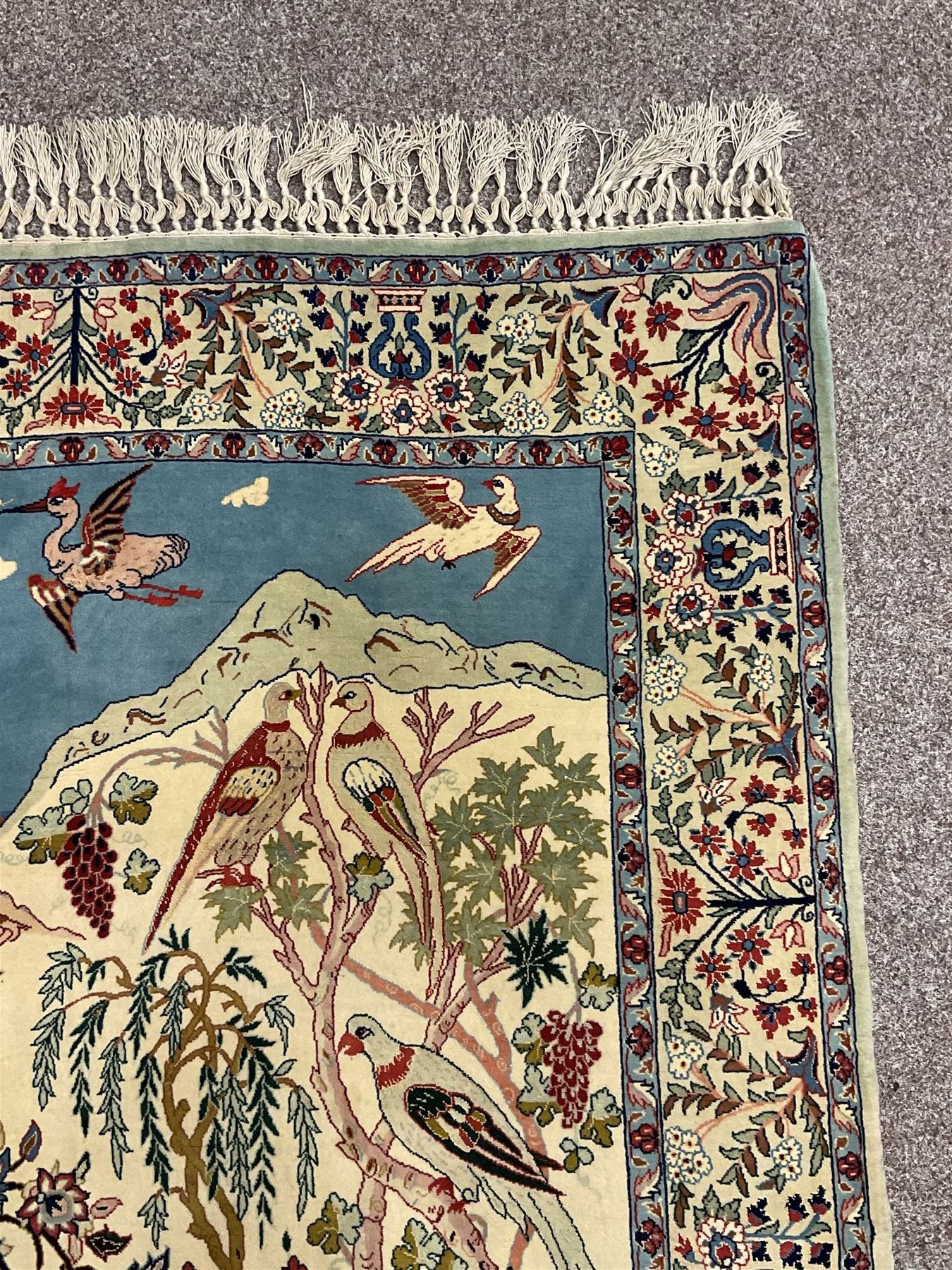 Fine Persian tree of life rug wall hanging, ivory ground field depicting landscape filled with animals, birds and flowers, the guarded border with stylised flower heads and foliage decoration, with brass hanging rail