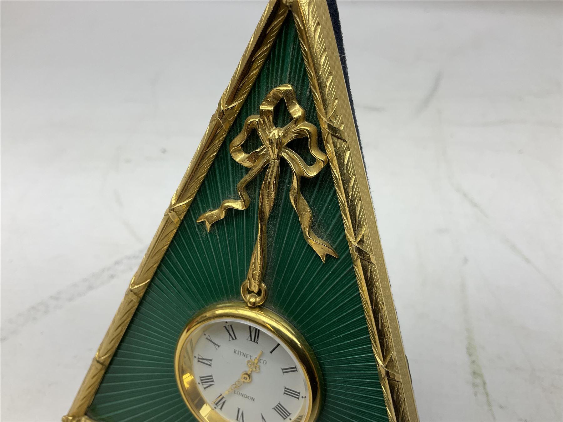 Kitney & Co small desk clock, in green guilloche enamel case of triangular form, decorated with gilt throughout, raised upon two bun feet, H12cm