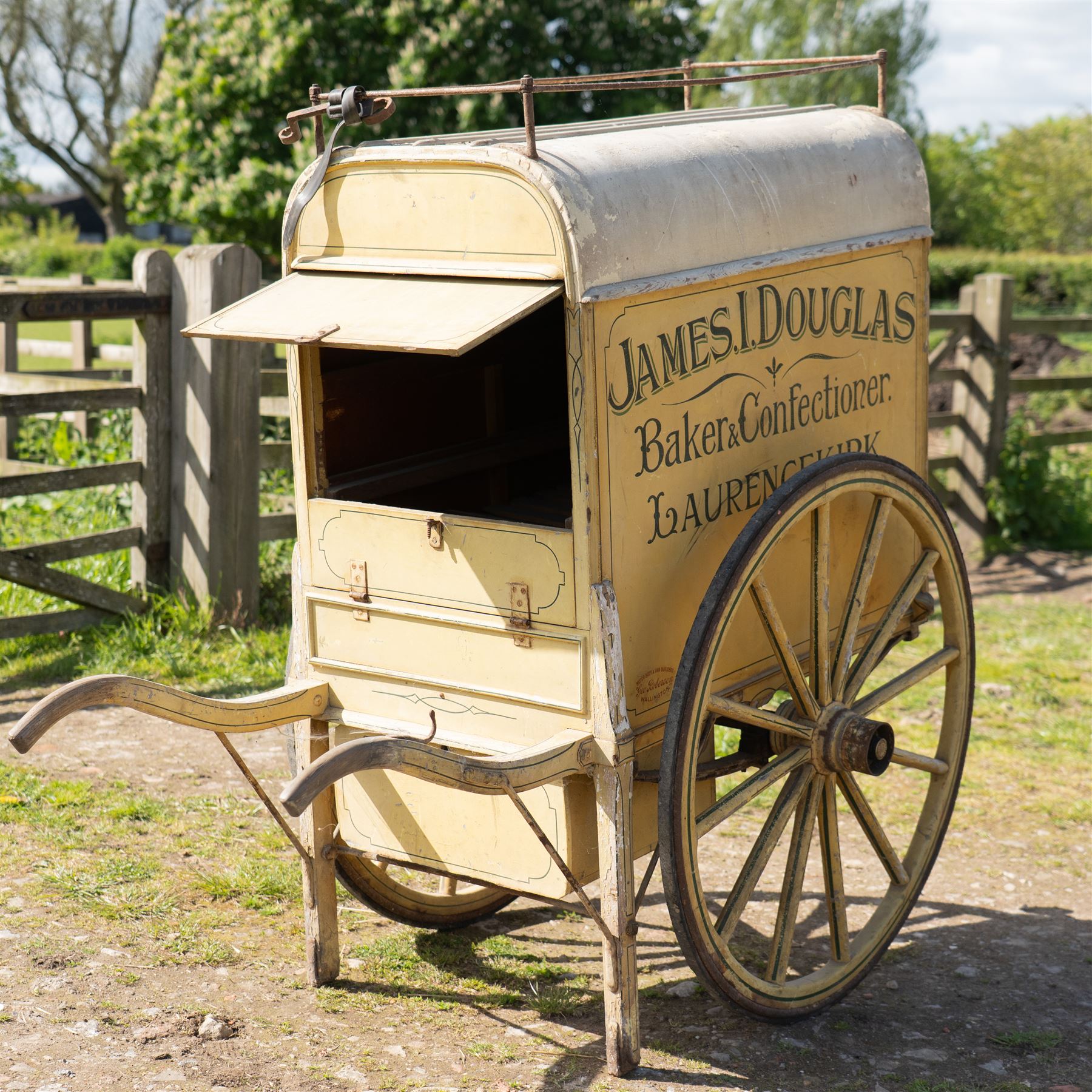 James I. Douglas, Baker & Confectioner, Laurencekirk Hand Drawn Delivery Cart

An attractive late 19th or early 20th century hand drawn baker's delivery cart, finished in cream and retaining its original hand painted advertising livery for James I. Douglas, Baker & Confectioner, Laurencekirk. The enclosed body features a curved roof with external luggage rail, rear access doors and internal shelving for the transport and delivery of bread, cakes and confectionery. Mounted on large wooden spoked wheels with iron tyres and fitted with shaped shafts for a single horse, this is a highly decorative and increasingly scarce example of a provincial tradesman's delivery vehicle, offering excellent display potential for collectors, museums, period interiors or commercial settings.

Features:
• Original hand painted signwriting for James I. Douglas, Baker & Confectioner, Laurencekirk
• Enclosed delivery body with curved roof and external luggage rail
• Rear opening access doors with internal storage compartments
• Original internal wooden shelving and racks
• Large wooden spoked wheels with iron tyres
• Shaped shafts for single horse traction
• Builder's mark for Geo. Roberson Ltd., Wallington
• Decorative cream painted finish with period lining and detailing
• Suitable as a display piece, museum exhibit or advertising feature

Dimensions:
Overall length: 170 cm
Body length: 104 cm
Width: 83 cm
Height: 150 cm

Wheel Diameter:
Wheels: 95 cm