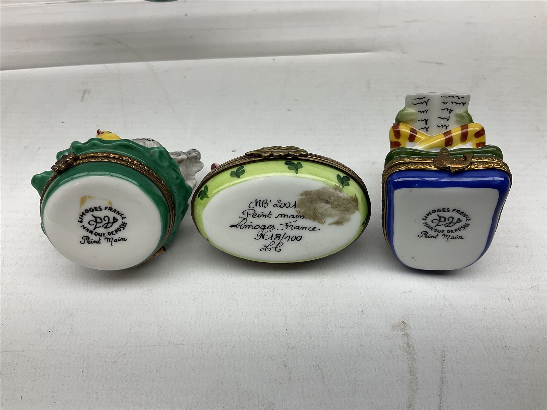 Group of Limoges trinket boxes, to include a number of novelty examples, including examples modelled as Noah's ark, shotgun case containing shotguns, picnic basket containing food, toad reading book seated upon a lily pad, etc., (9)