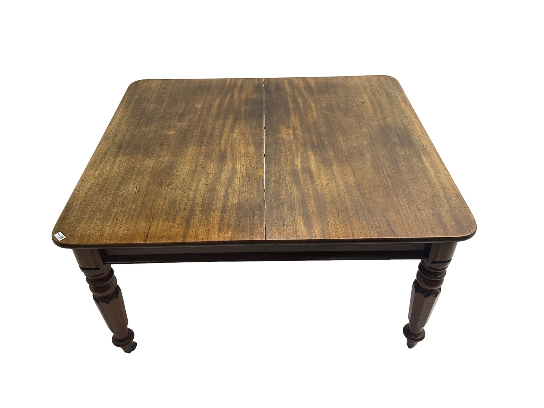Late 19th century extending mahogany dining table, square top with banded frieze rail, raised on turned octagonal supports with  brass cups and castors, with two additional leaves