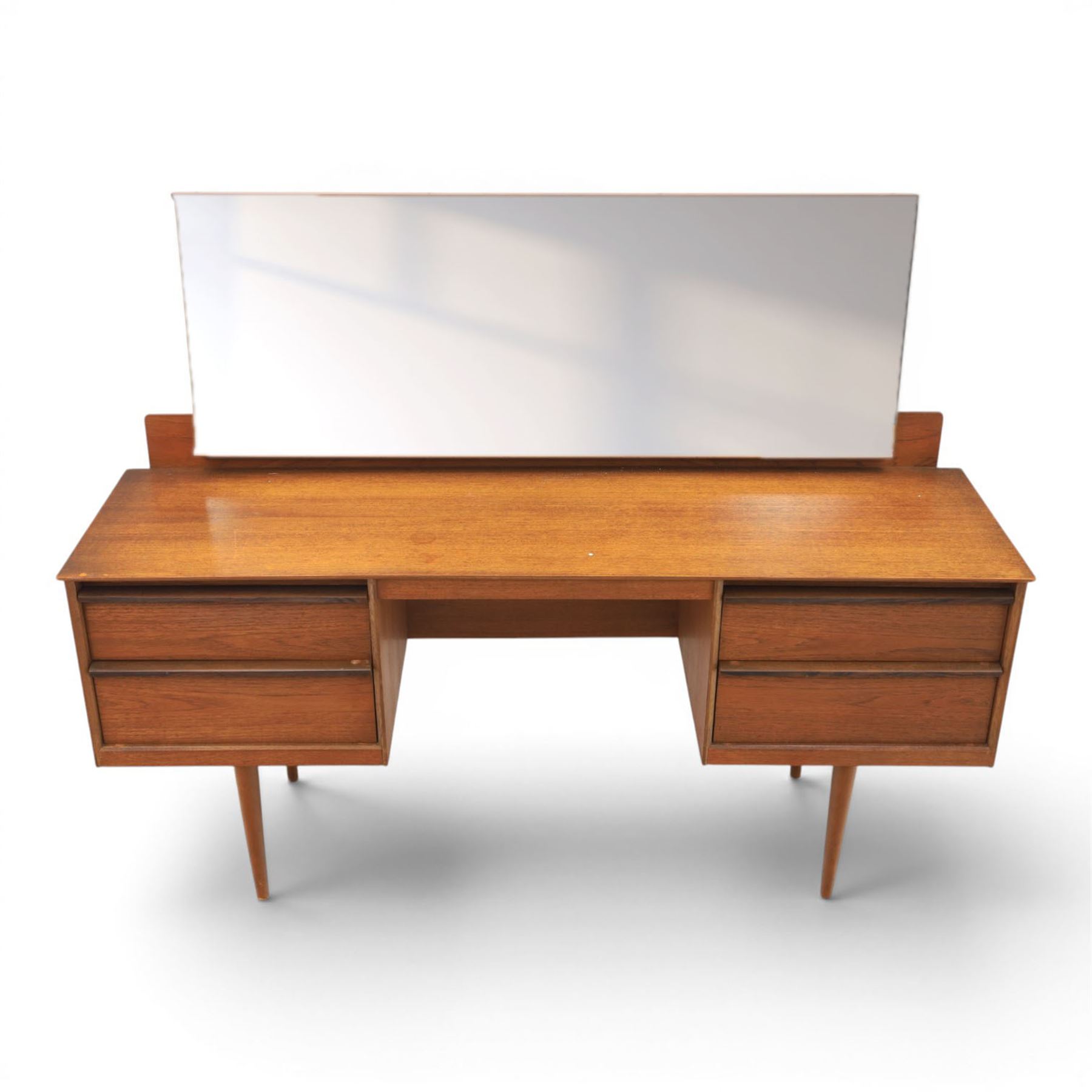 Austinsuite - mid 20th century teak headboard with bedside cabinets and matching  mirrored dressing table, the headboard with floating single drawer bedsides raised on a single tapering support, the dressing table with attached tilting mirror, above rectangular top with kneehole and two banks of two drawers, raised on tapering supports

Headboard H 84cm, D 40cm, W 229cm, W between bedsides 151cm 
Dressing table H 113cm D 44cm, W 149cm, H to underside of dresser 61cm