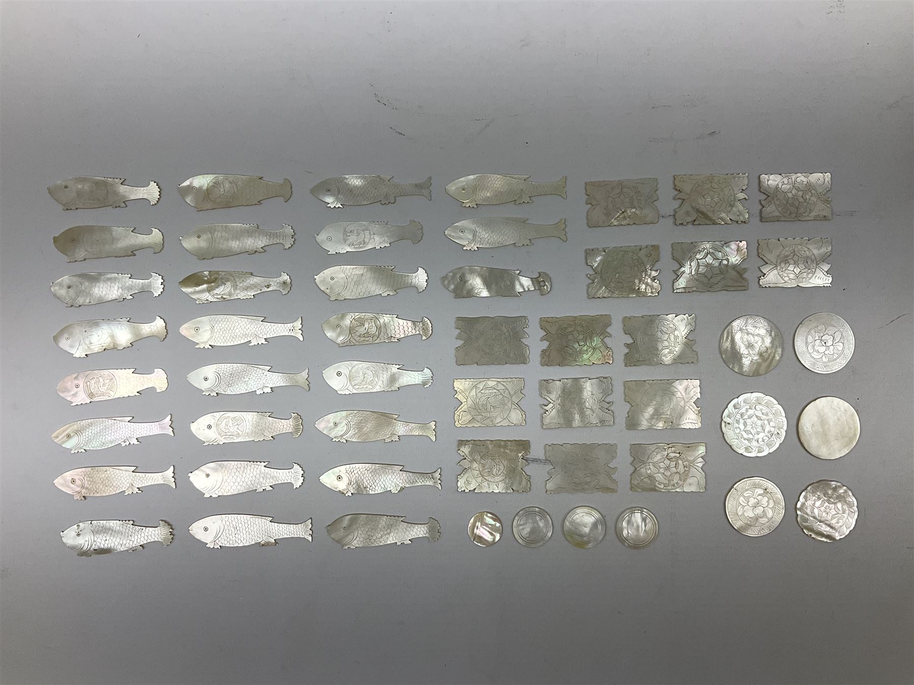Collection of fifty two Chinese mother of pearl gaming counters or tokens, of various size and form including rectangular, circular and fish shaped examples, various decoration including floral motifs, largest rectangular examples L4cm