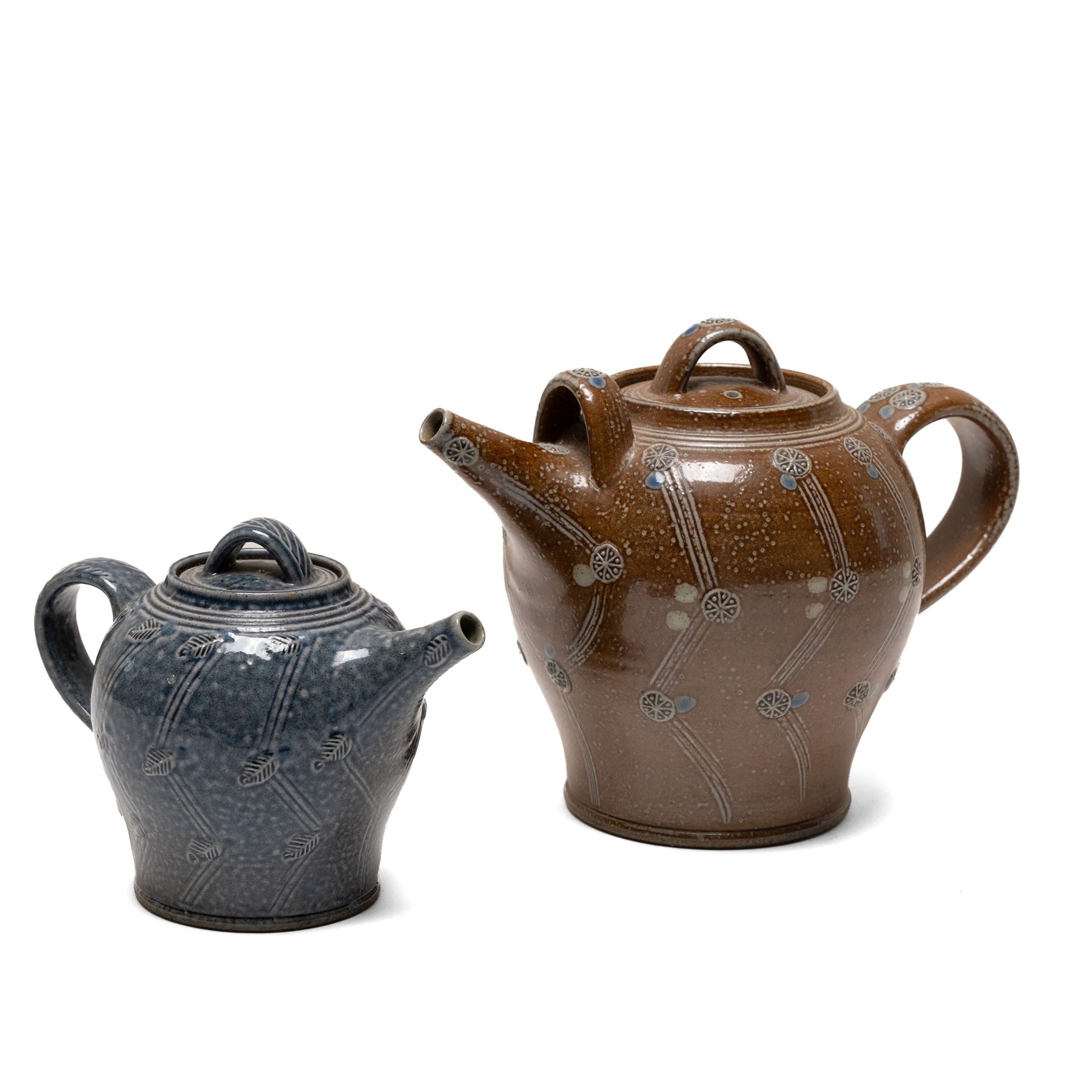 Gus Mableson - two studio pottery teapots, the larger example with a repeating floral pattern upon a brown ground, each with impressed makers marks below the handle, largest H18cm