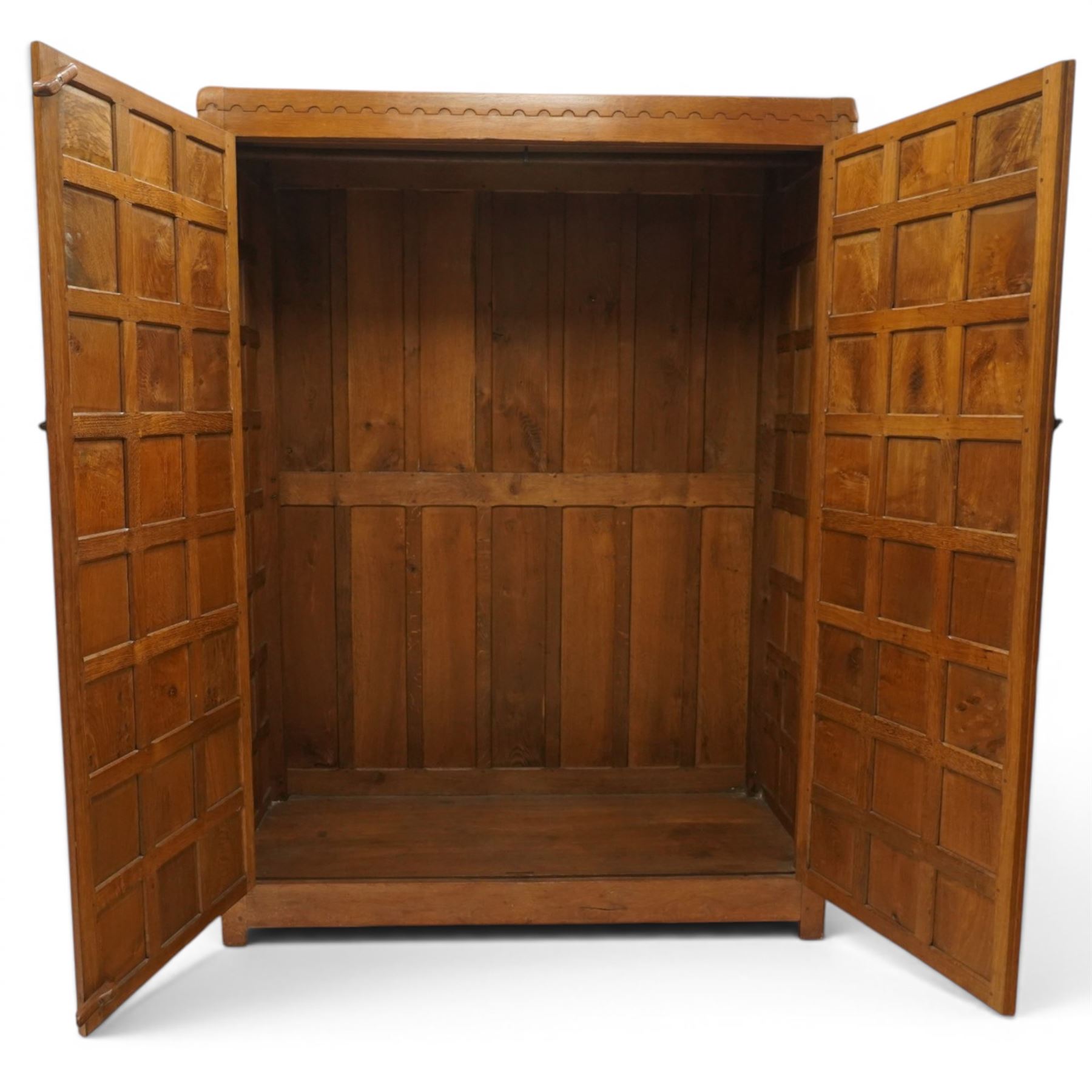 Mouseman - early-to-mid-20th century figured panelled and adzed double wardrobe of large proportions, the arcade carved cresting rail over two doors with adzed and figured oak panels, with wrought metal hinges and latch, relief carved mouse signature, the interior fitted with hanging rail, by the workshop of Robert Thompson, Kilburn