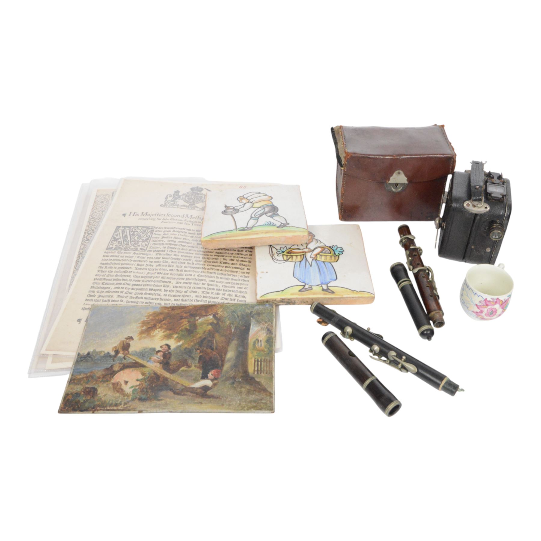 Pair of 20th century continental tin glazed tiles, of a man and a woman in traditional dress, H15cm, together with a Baby Cine Camera in case, flute parts, and Continental oil on board