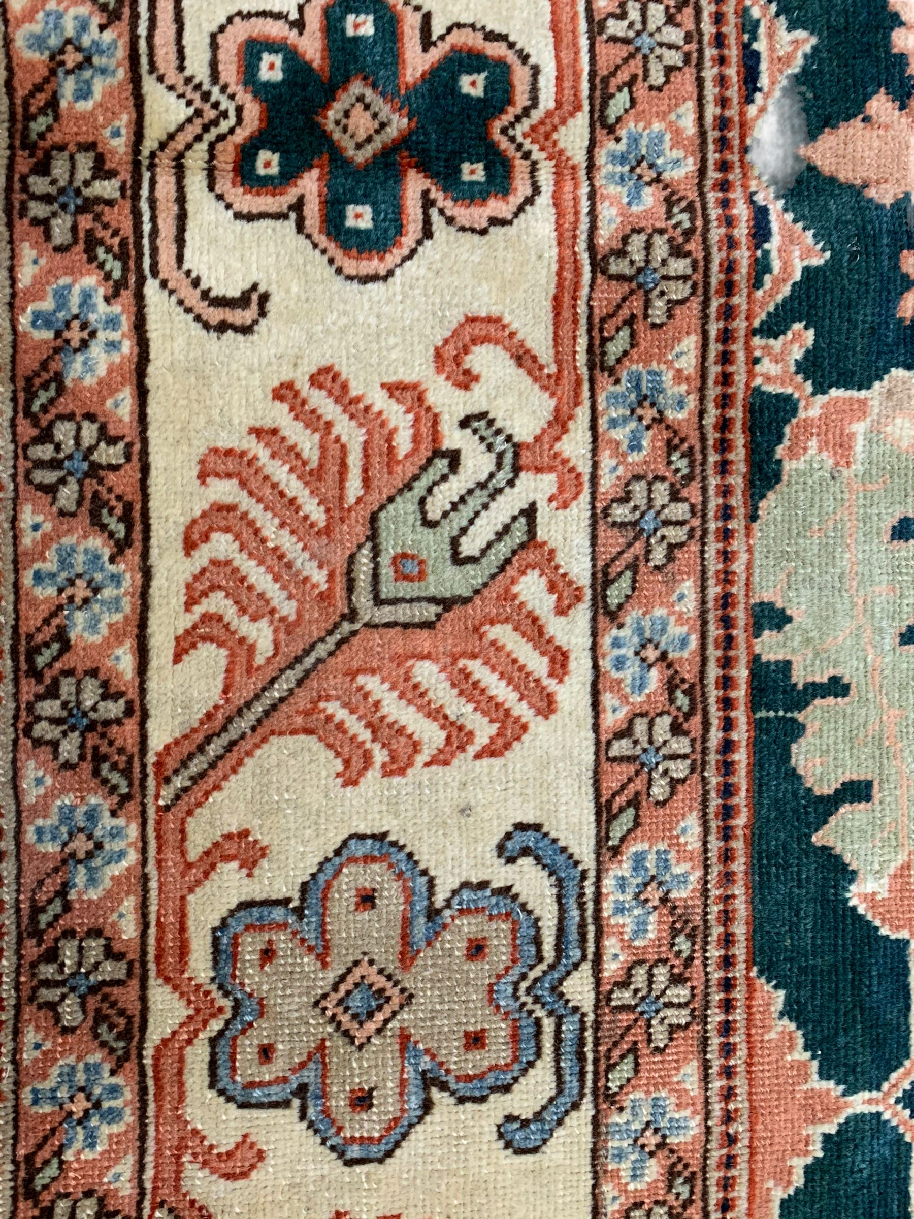 Persian emerald green ground rug, the field decorated with large stylised plant motifs, ivory ground border with repeating leaf motifs, the guards decorated with trailing branch and flowerhead motifs