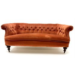 Victorian three seat settee upholstered in deep buttoned terracotta fabric, scrolling arms, turned tapering supports on castors