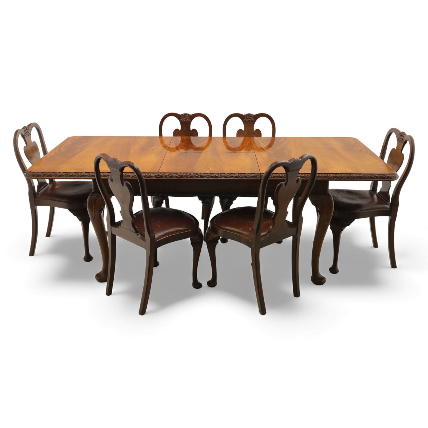 Queen Anne design walnut dining suite, comprising a rectangular dining table with carved moulded edge and rounded corners, raised on cabriole legs terminating in pad feet, together with a set of six matching dining chairs, each with shaped splat back, leather upholstered seat and cabriole supports (Extends to 230cm)