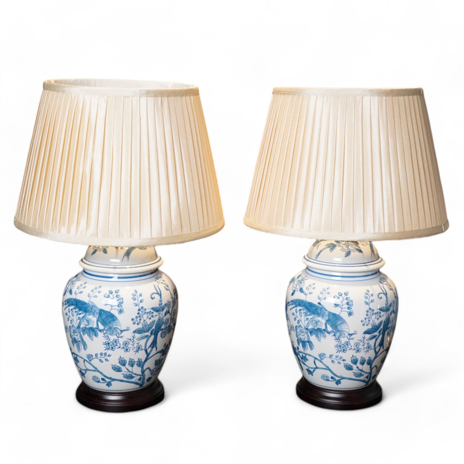 Pair of table lamps of baluster form, decorated with exotic birds up fruiting trees, on hardwood pedestals, H55cm including shades