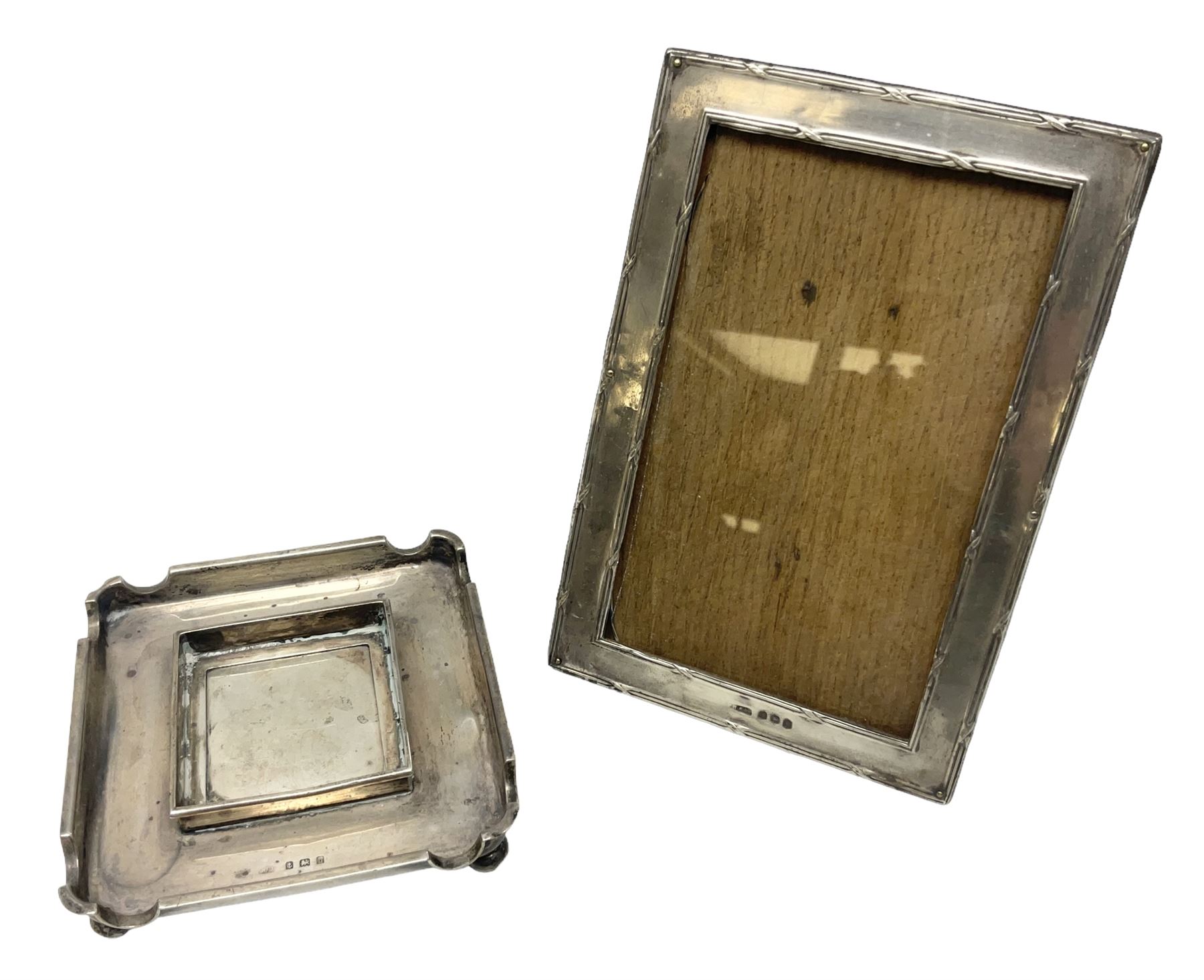Edwardian silver stand, of square shaped form, upon four bun feet, hallmarked Birmingham 1907, together with an early 20th century silver mounted photograph frame, hallmarked Birmingham 1918, approximate weighable silver 93.6 grams