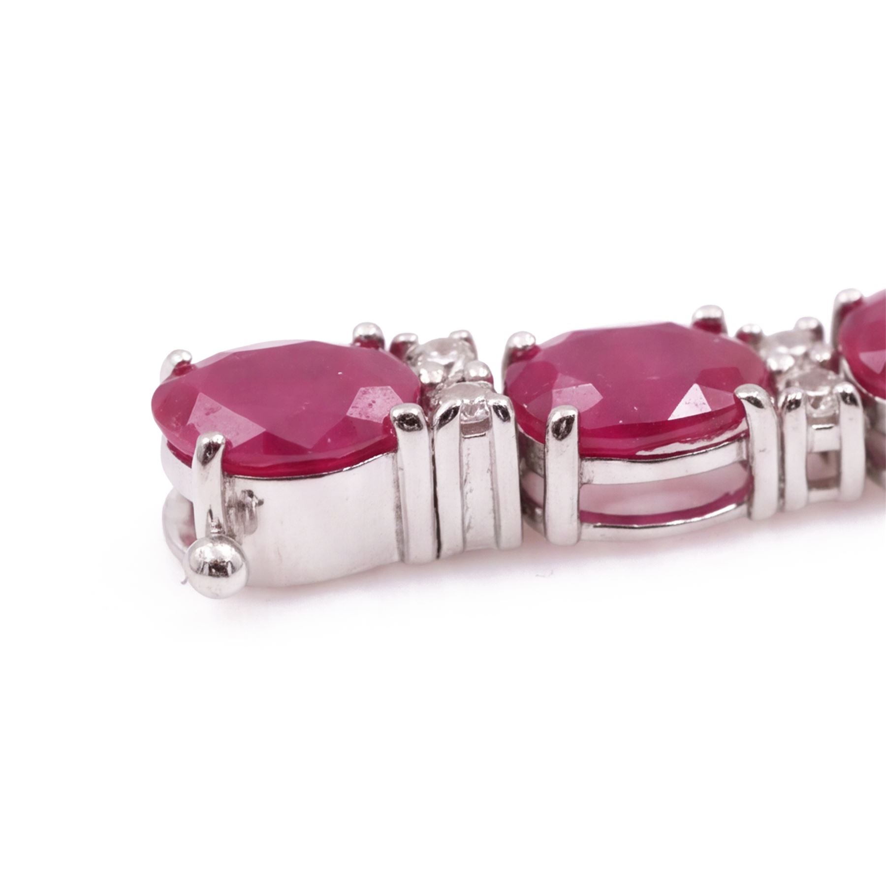 18ct white gold ruby and diamond bracelet, twenty-six oval cut rubies, each spaced by two round brilliant cut diamonds, stamped 750, total ruby weight 12.70 carat, total diamond weight 0.46 carat