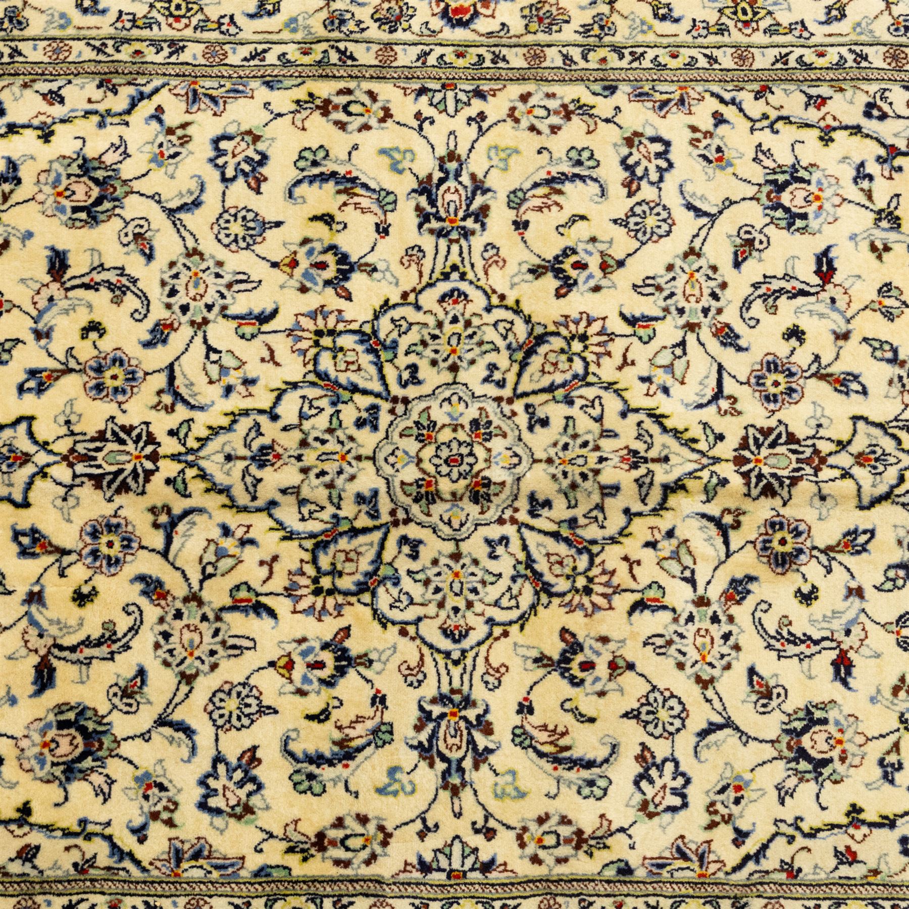 Central Persian Kashan hand-knotted rug, ivory ground, with a small central floral medallion and pendants, the field finely decorated with blue, cream and soft red scrolling vines, flowerheads and palmettes, within an ivory floral border and narrow guard stripes, with cotton fringes