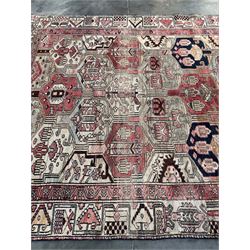 Persian Heriz red and pale ground rug, depicting multiple shaped panels with stylised motifs and designs, geometric patterned border