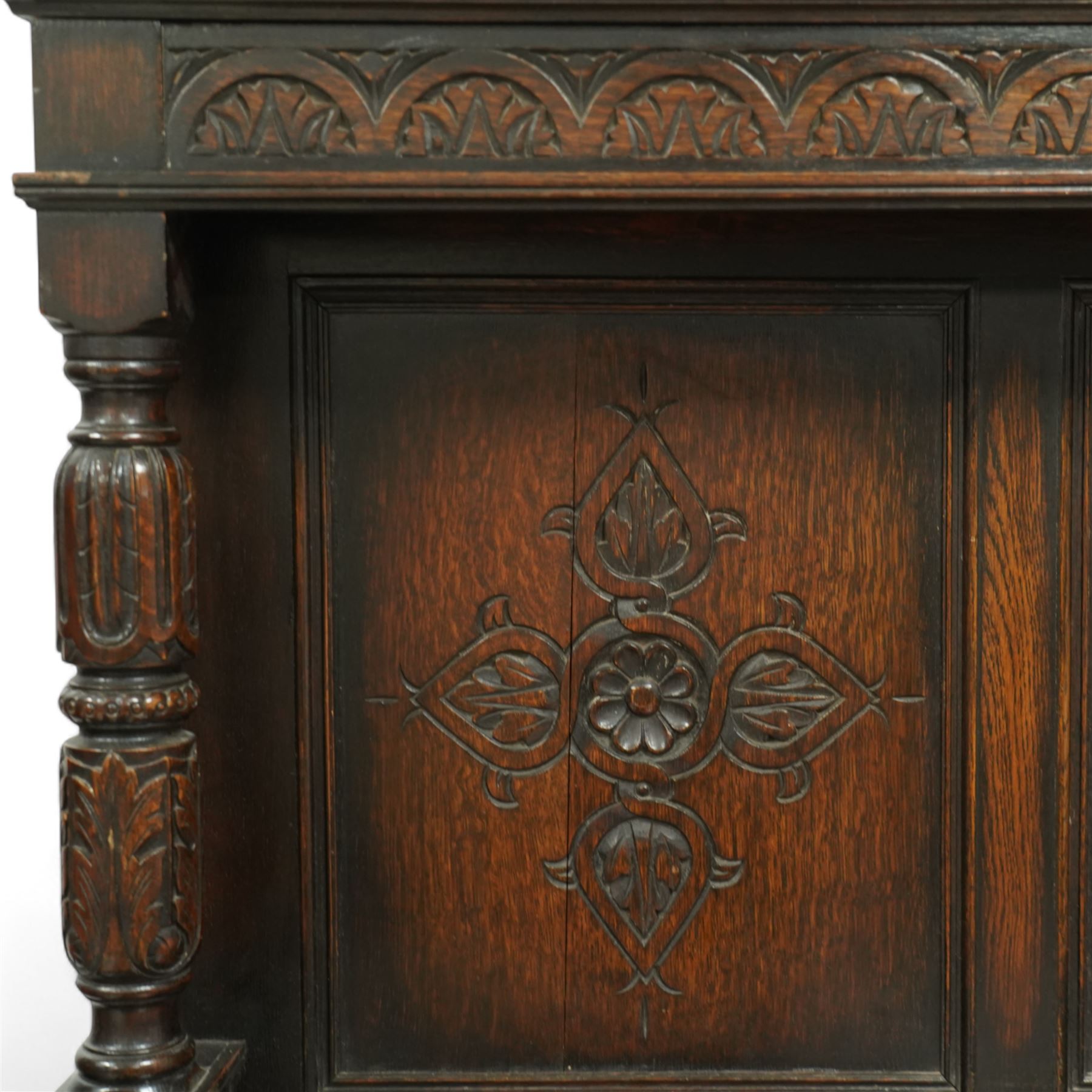 Early 20th century carved oak sideboard Jacobean style with panel back on cup and cover legs, the top section with carved panels and reeded moulding, three deep frieze drawers over triple panelled cupboard doors, raised on carved baluster legs joined by lower shelf