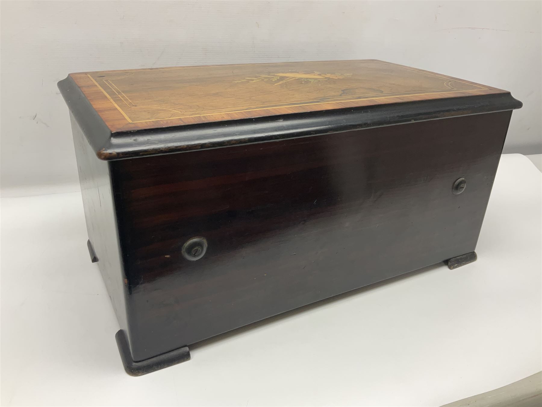 Large late 19th century Swiss bells-in-sight musical box with 27.5cm cylinder playing eight airs on a 27cm two-piece comb with seventy-seven teeth and six graduated engraved saucer bells with strike/silent facility; in crossbanded rosewood and ebonised case, the front and hinged lid inlaid with musical trophies, opening to reveal a song card under the lid and hinged glazed cover to the movement; serial no.7539 L53cm