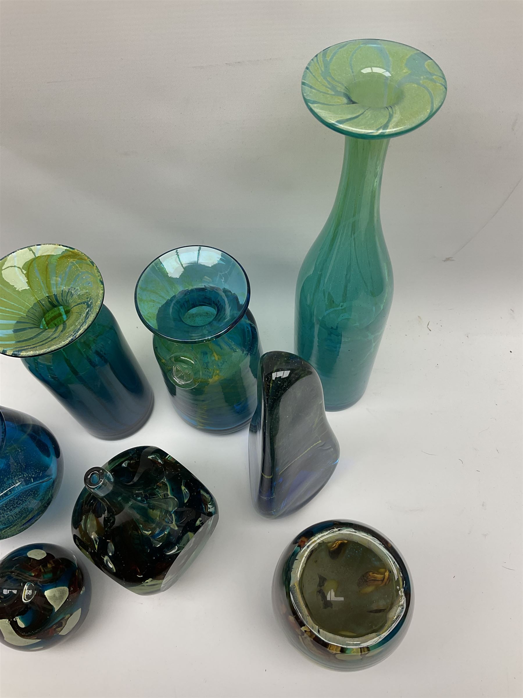 Quantity of M’dina art glass to include a streaked blue and green bottle form vase with captured bubble design and slender neck, H35cm, along with a paperweight, ovoid form vase and another vase all decorated in a blue, brown and white colour way, other contemporary glass examples etc with etched marks beneath