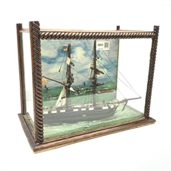 Victorian scratch built water-line model of a two-masted sailing ship with wooden hull and furled sails L31cm in glazed display case with rope twist mounts, the backboard painted with a coastal harbour scene L37cm H29cm D22cm