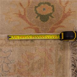 West Persian hand-knotted Ziegler design rug, ivory field decorated with an all-over lattice of stylized palmettes and floral sprays linked by angular vines, border of scrolling floral ornamentation in a palette of blush pink, sage green, powder blue, and soft ochre, with cotton fringe ends 