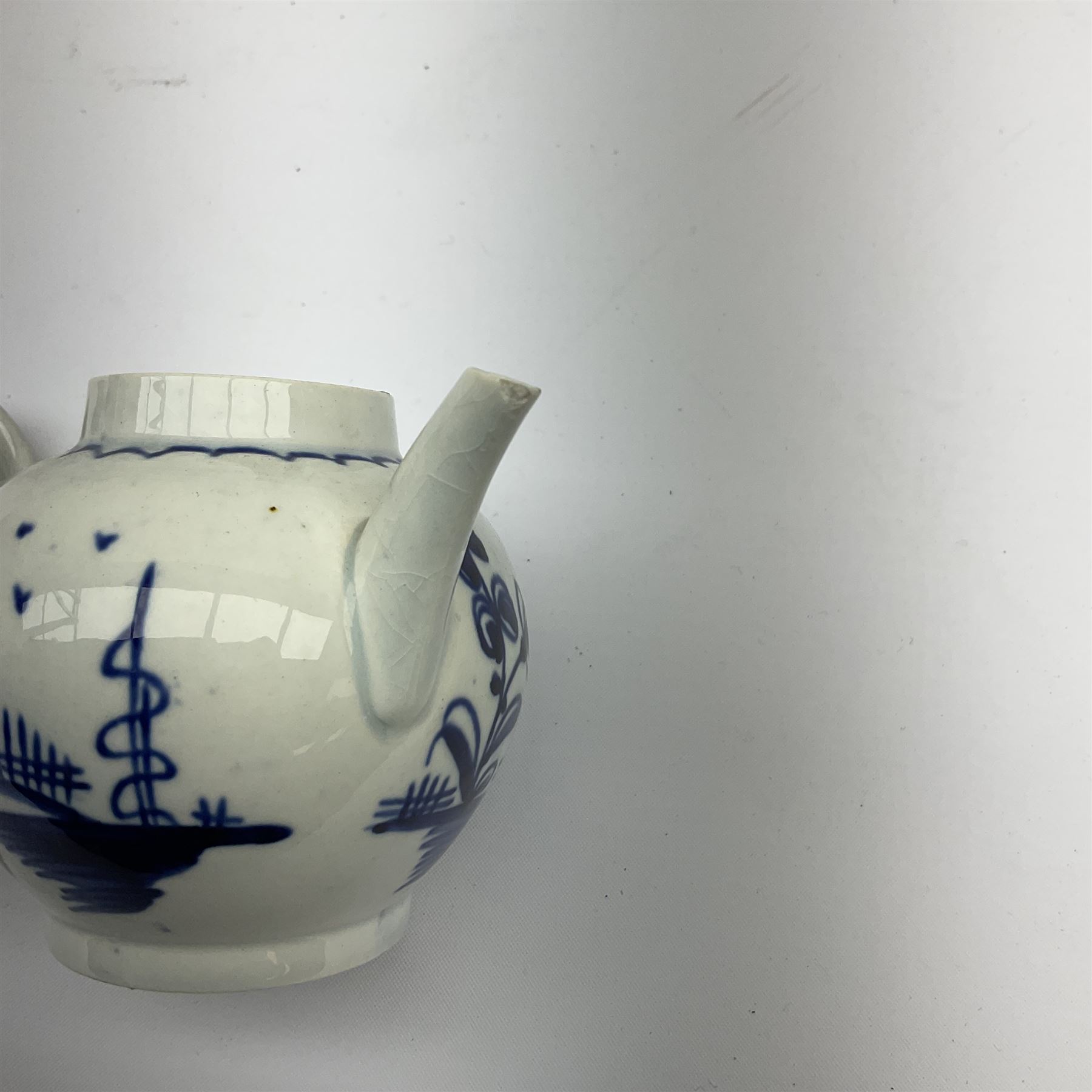 Two 18th century miniature or toy pearlware teapots, the first example lacking cover decorated with an exotic bird, the second with cover painted in underglaze blue with hut and fence, second example approximately H8cm