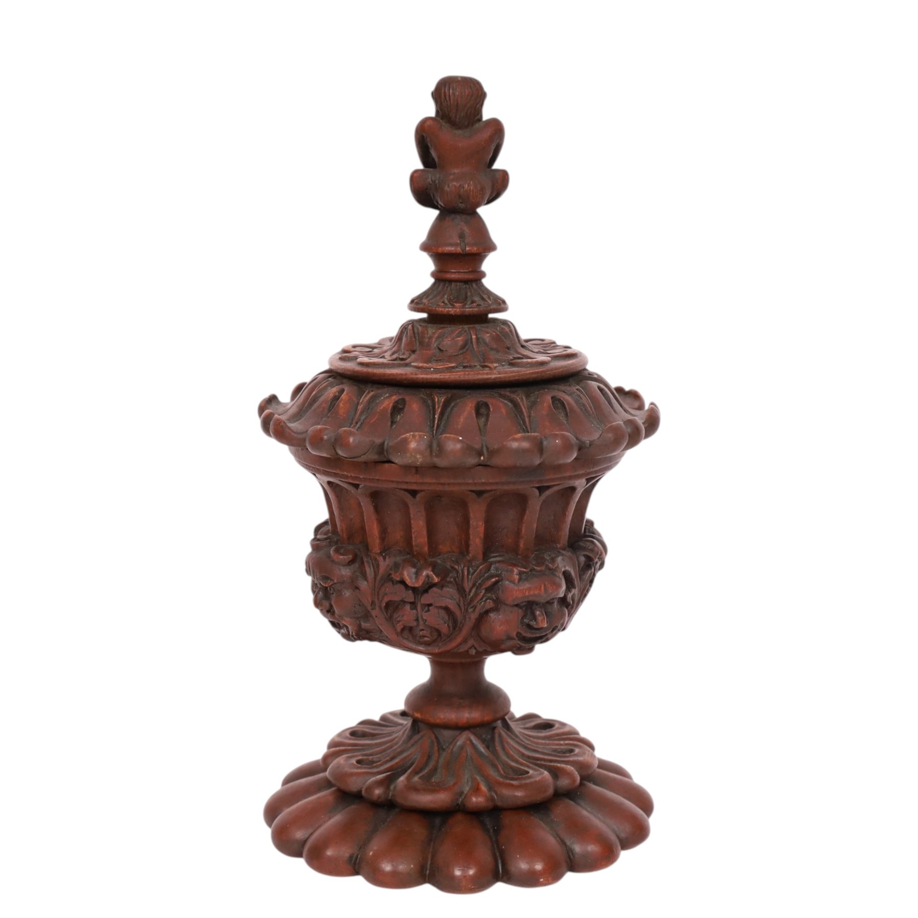Carved wooden urn. decorated in relief with carved faces within foliage, with a Satyr finial, H25cm 
