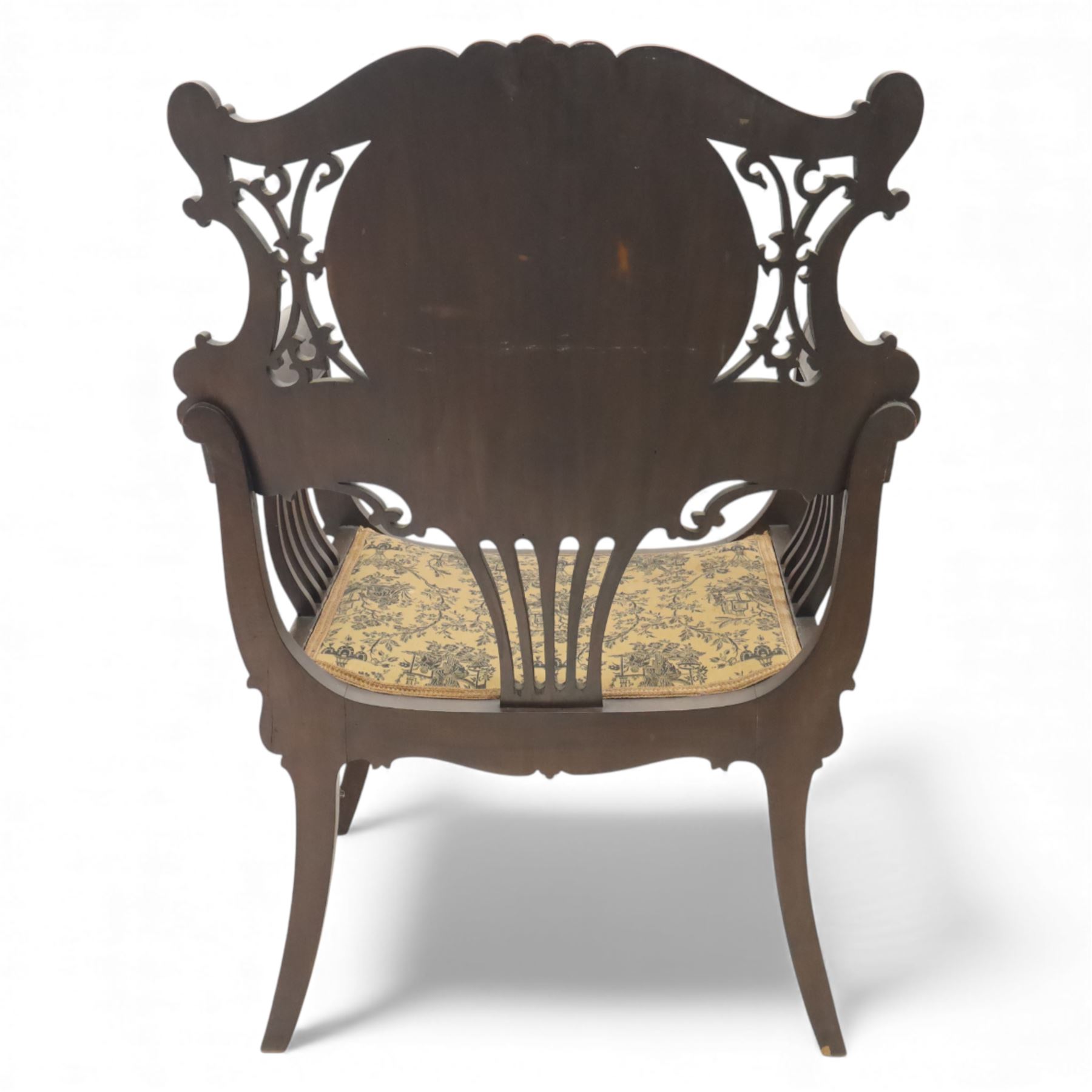 Art Nouveau mahogany open armchair in the manner of Shapland & Petter, the shaped and pierced back with foliate cresting and central panel inlaid with stylised marquetry plume, curved arms over upholstered seat, raised on sabre legs