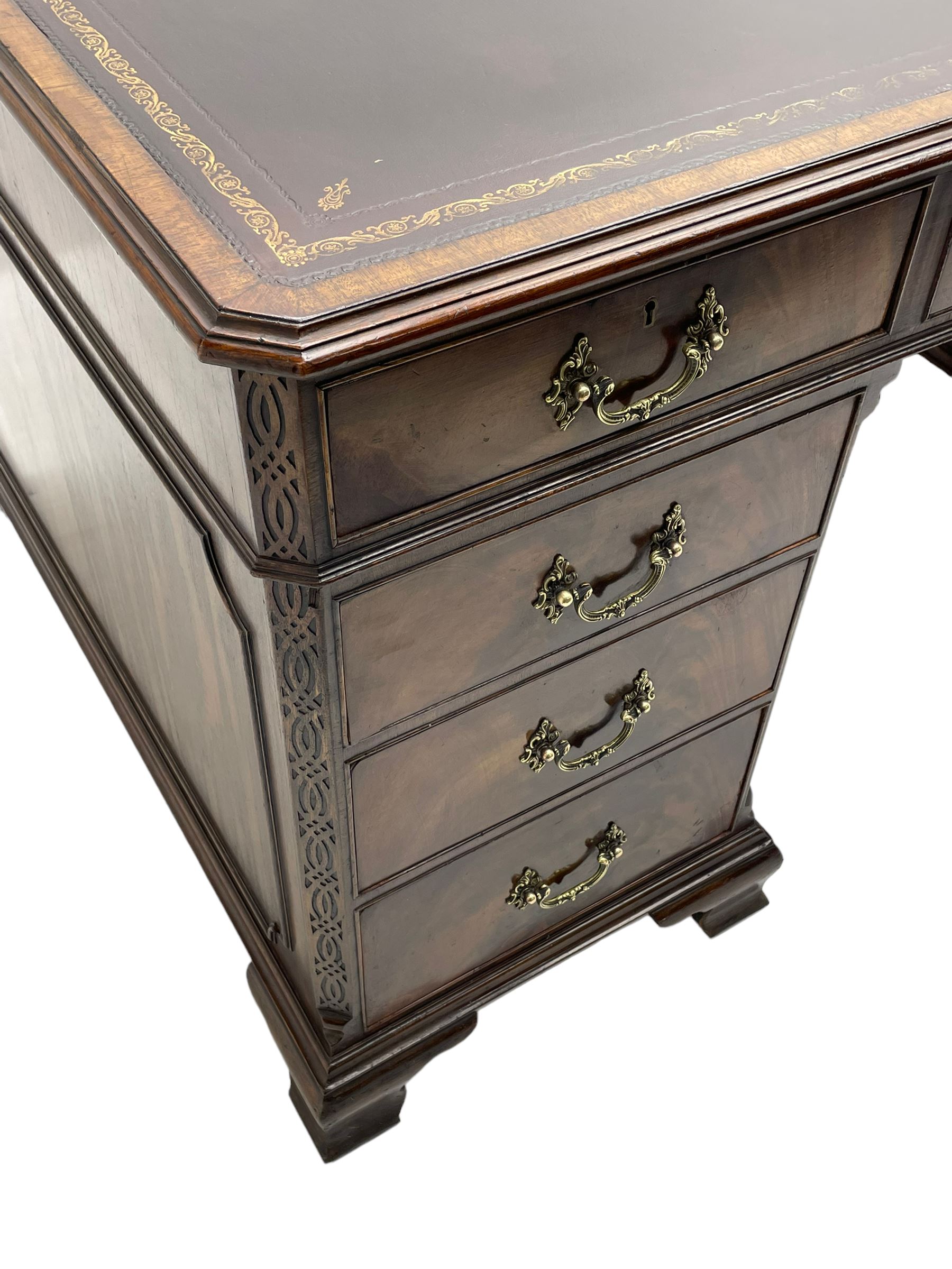 Large Georgian design mahogany twin pedestal partner's desk, moulded rectangular top with canted corners and inset leather writing surface, fitted with nine drawers and two cupboards, the pedestals with canted uprights decorated with blind fretwork, on ogee bracket feet