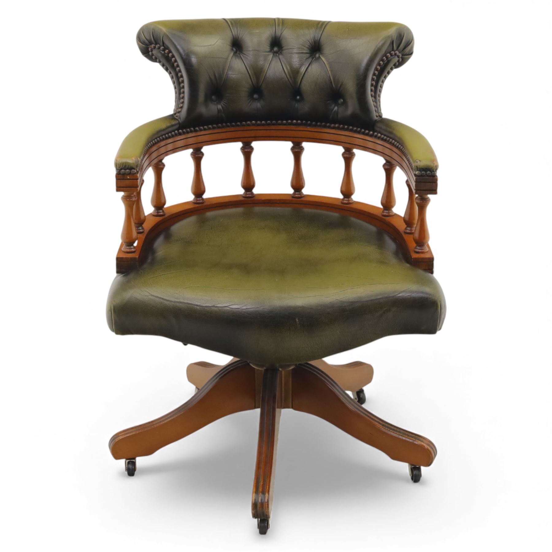 Late 20th century swivel captain’s desk chair, green buttoned vinyl upholstered back and seat with brass stud edging, the spindle gallery over a rotating base with five splayed supports on castors